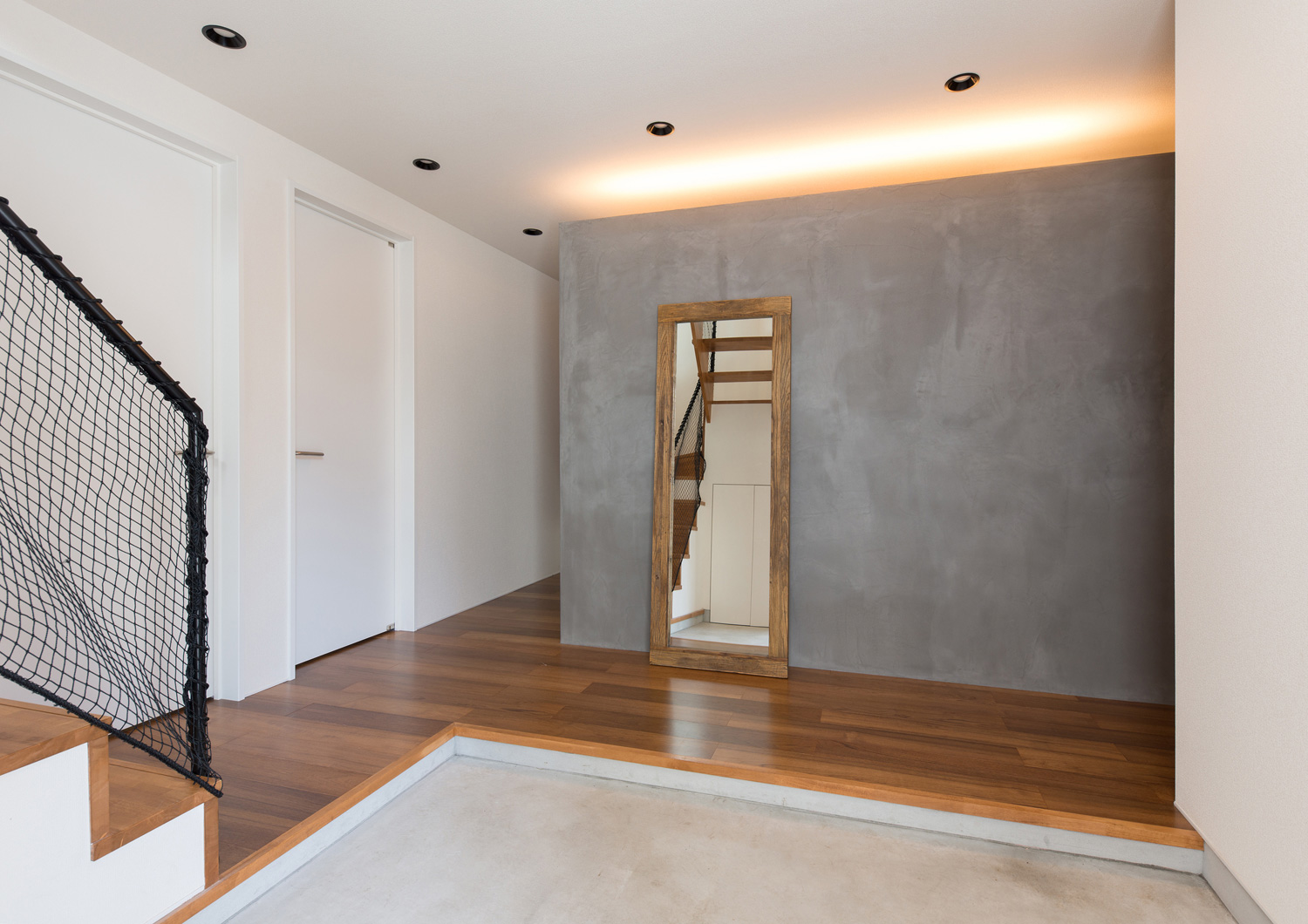 モルタルの玄関の正面にグレーの壁と鏡がある様子・デザイン住宅 注文住宅・デザイン住宅建築実例_『CASE582 大切な時を刻む家』_玄関