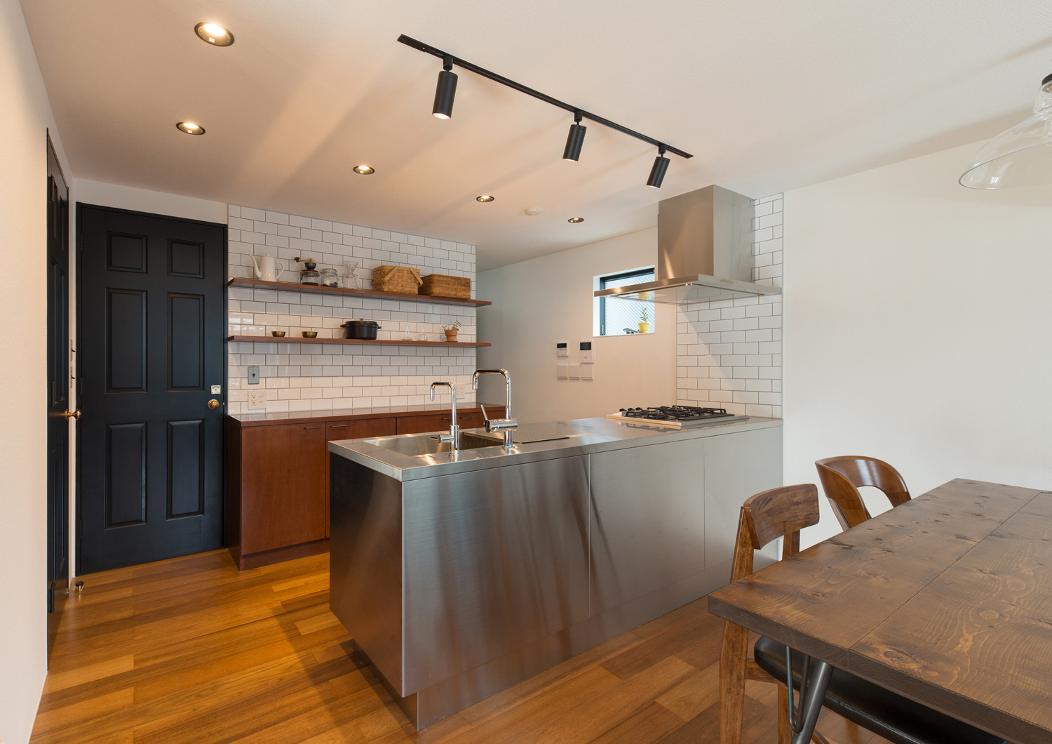 ステンレスのペニンシュラキッチンの正面に木のダイニングテーブルが置かれた様子・デザイン住宅 注文住宅・デザイン住宅建築実例_『CASE582 大切な時を刻む家』_LDK