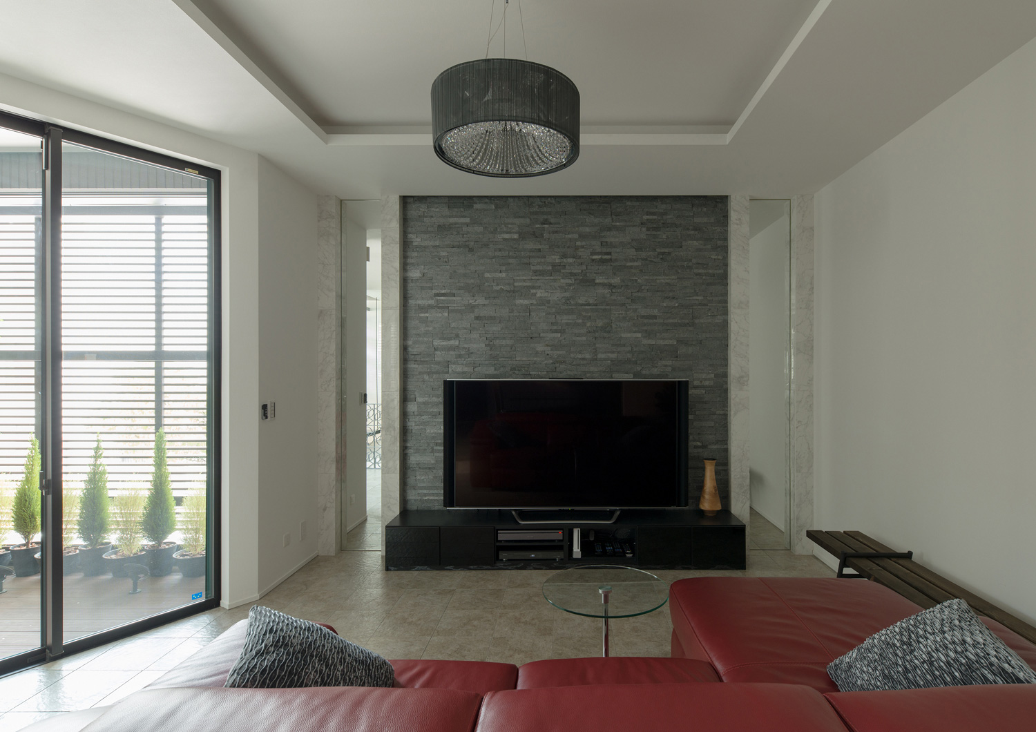 黒いタイルのアクセントウォールの前にテレビを置いた大理石の床のLDK・デザイン住宅 注文住宅・デザイン住宅建築実例_『CASE585 いしのいえ』_LDK