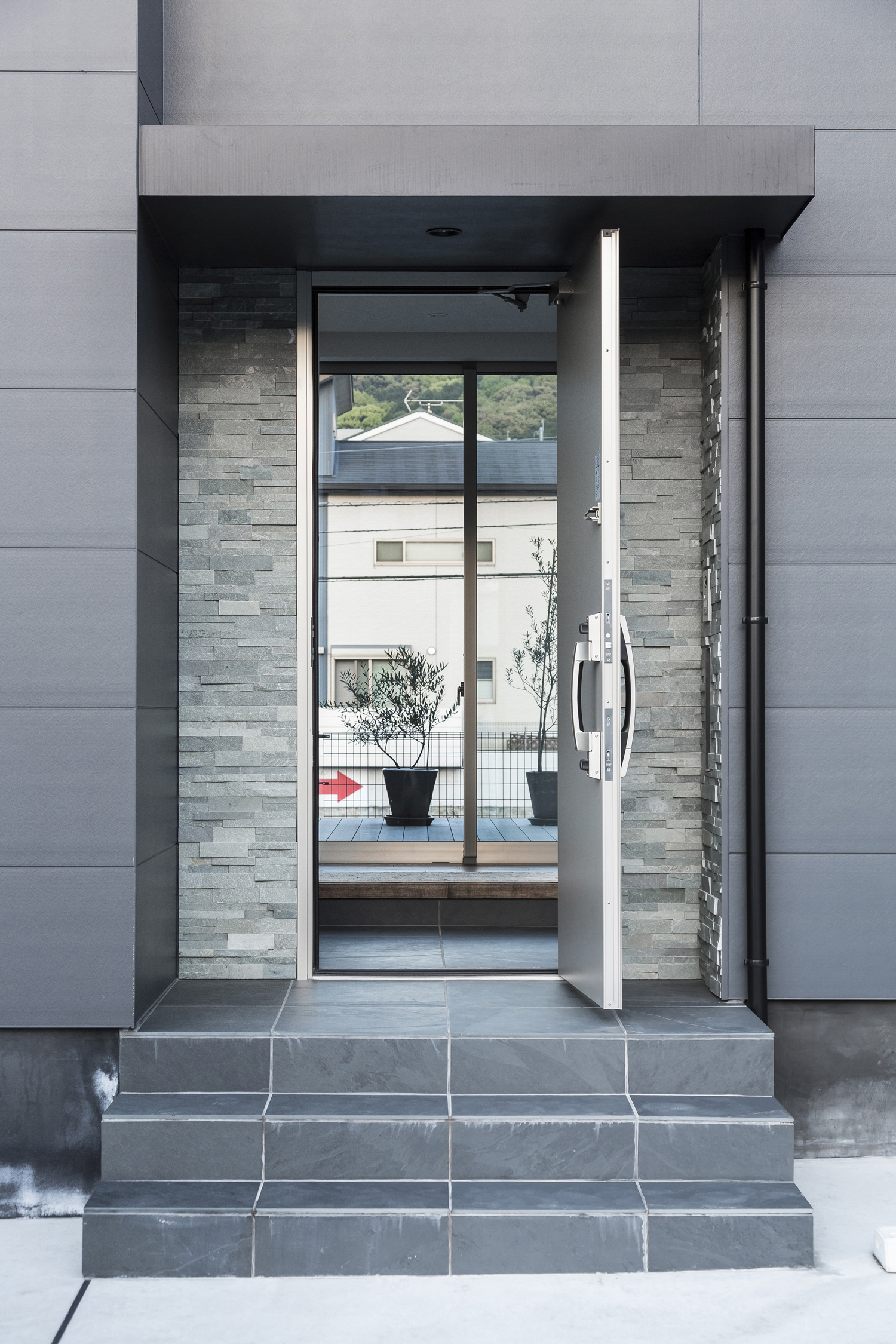 タイルの階段アプローチの先にある玄関扉が開いている様子・デザイン住宅 注文住宅・デザイン住宅建築実例_『CASE587 Nero』_外観