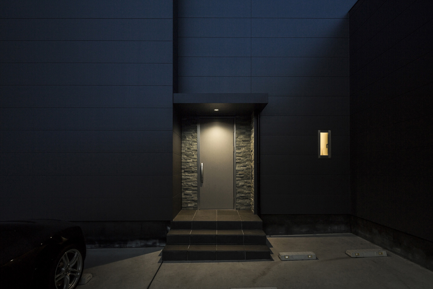 タイルのアクセントウォールに玄関扉が取り付けられた黒い外壁の家・デザイン住宅 注文住宅・デザイン住宅建築実例_『CASE587 Nero』_外観