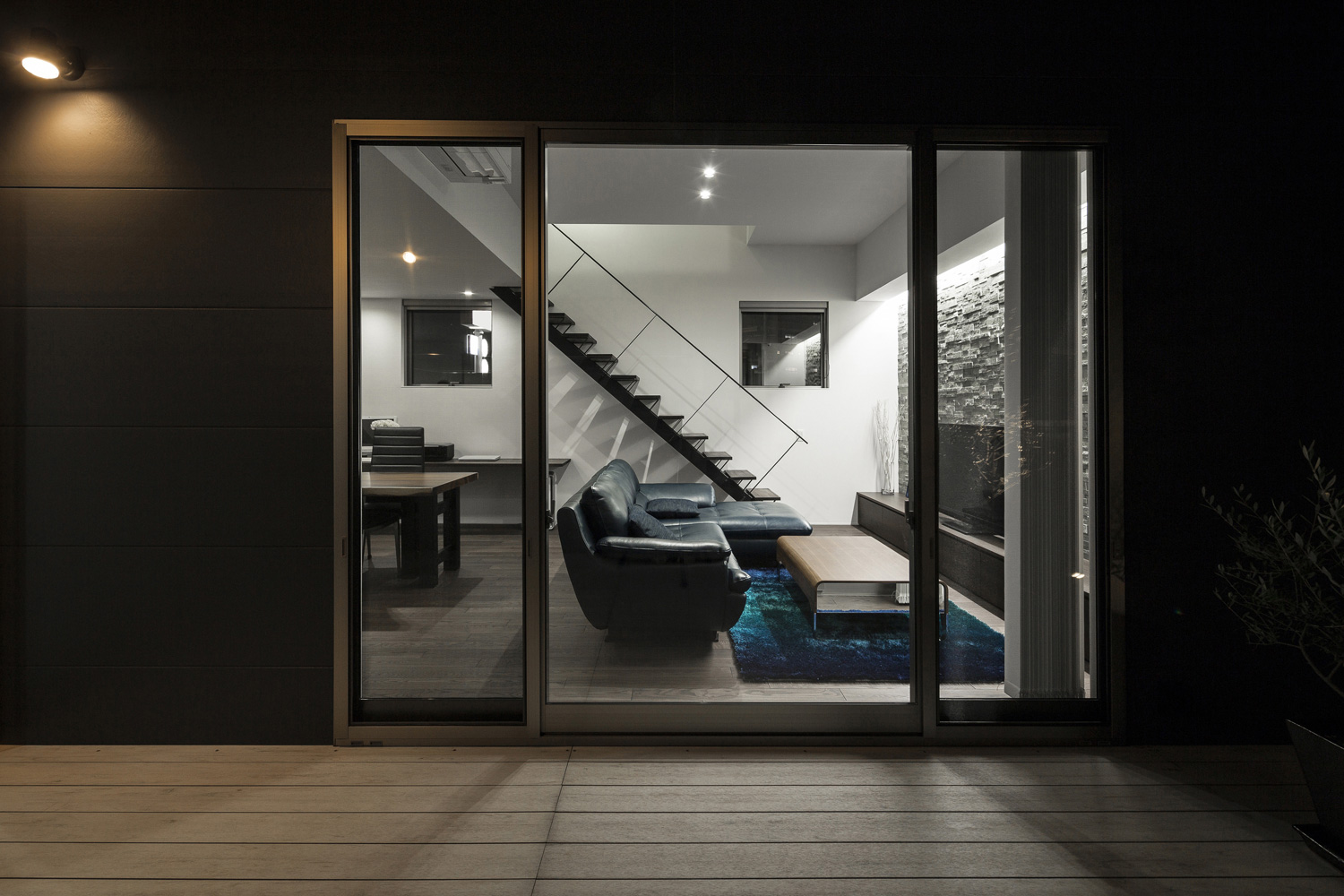 壁に照明が取り付けられた中庭からLDKを見た様子・デザイン住宅 注文住宅・デザイン住宅建築実例_『CASE587 Nero』_中庭