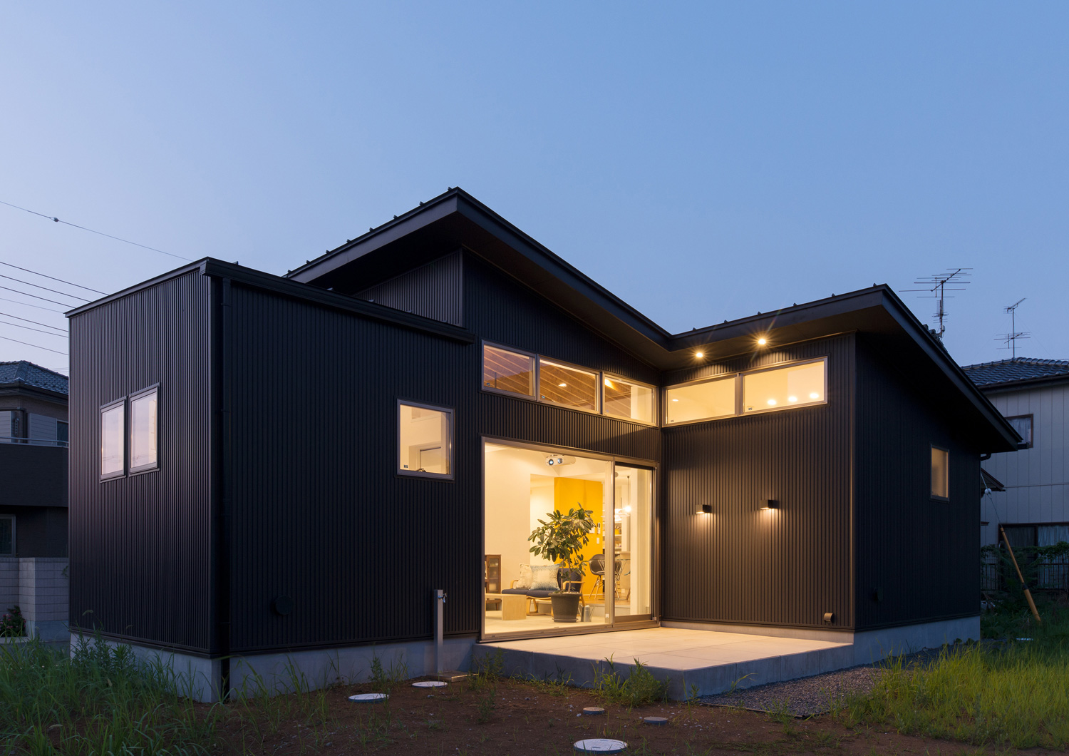 壁に照明が取り付けられたタイルのテラスがある黒い外壁の平屋住宅・デザイン住宅 注文住宅・デザイン住宅建築実例_『CASE588 涅の櫂』_外観