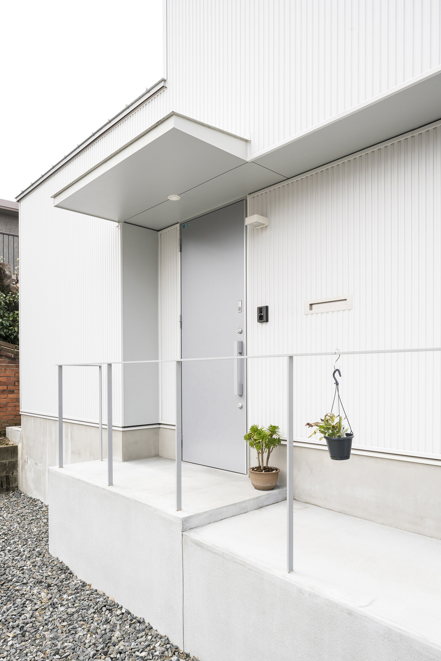 窓のない白い外壁にグレーの玄関扉が取り付けられた家・デザイン住宅 注文住宅・デザイン住宅建築実例_『CASE589 pinwheel』_外観