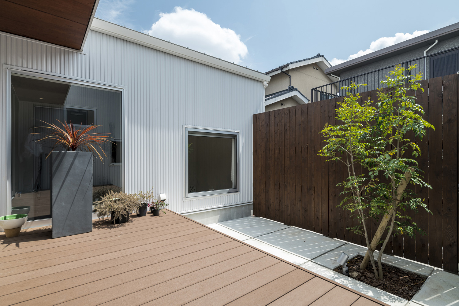 ウッドデッキ部分とコンクリート部分が分かれた、植栽や木の目隠しがある中庭・デザイン住宅 注文住宅・デザイン住宅建築実例_『CASE589 pinwheel』_中庭