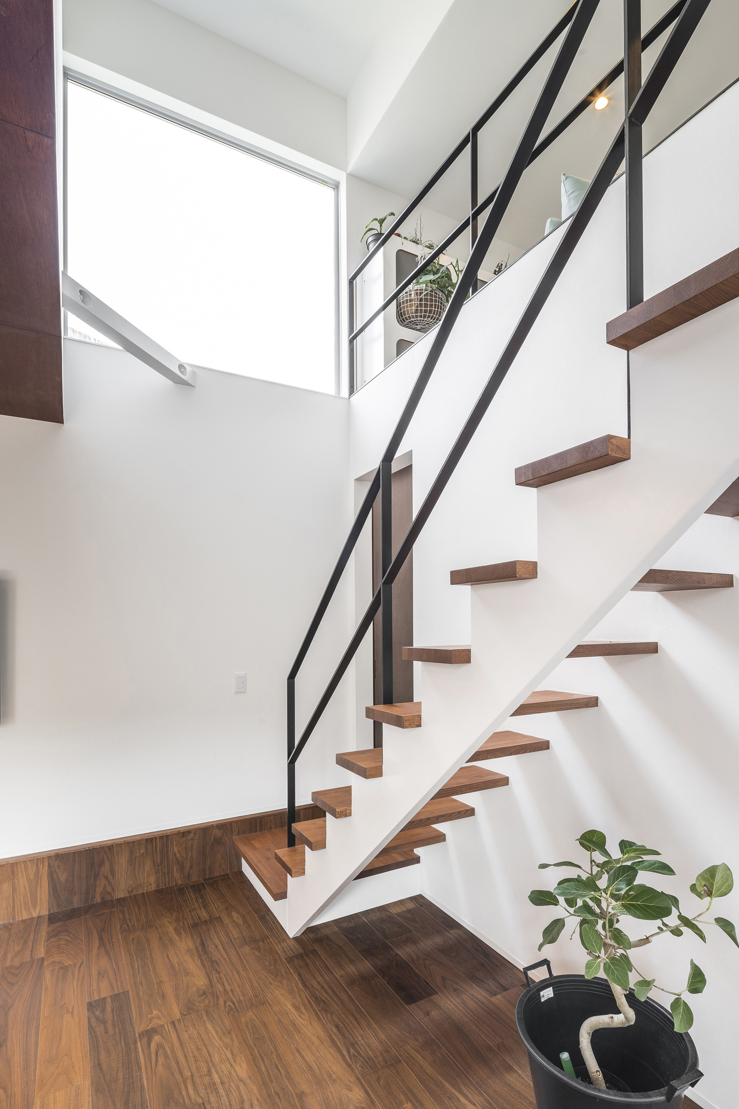 窓が設けられた吹き抜け部分にある、アイアンの手すり付きのリビングイン階段・デザイン住宅 注文住宅・デザイン住宅建築実例_『CASE589 pinwheel』_階段