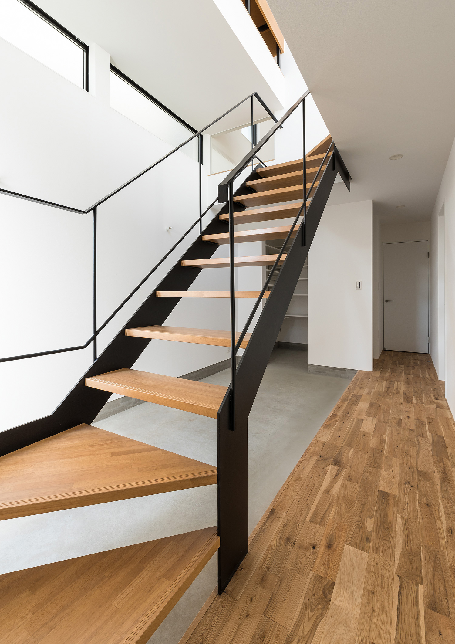 モルタルの玄関の上を横切る木製のスケルトン階段・デザイン住宅 注文住宅・デザイン住宅建築実例_『CASE590 つなぐ家』_階段