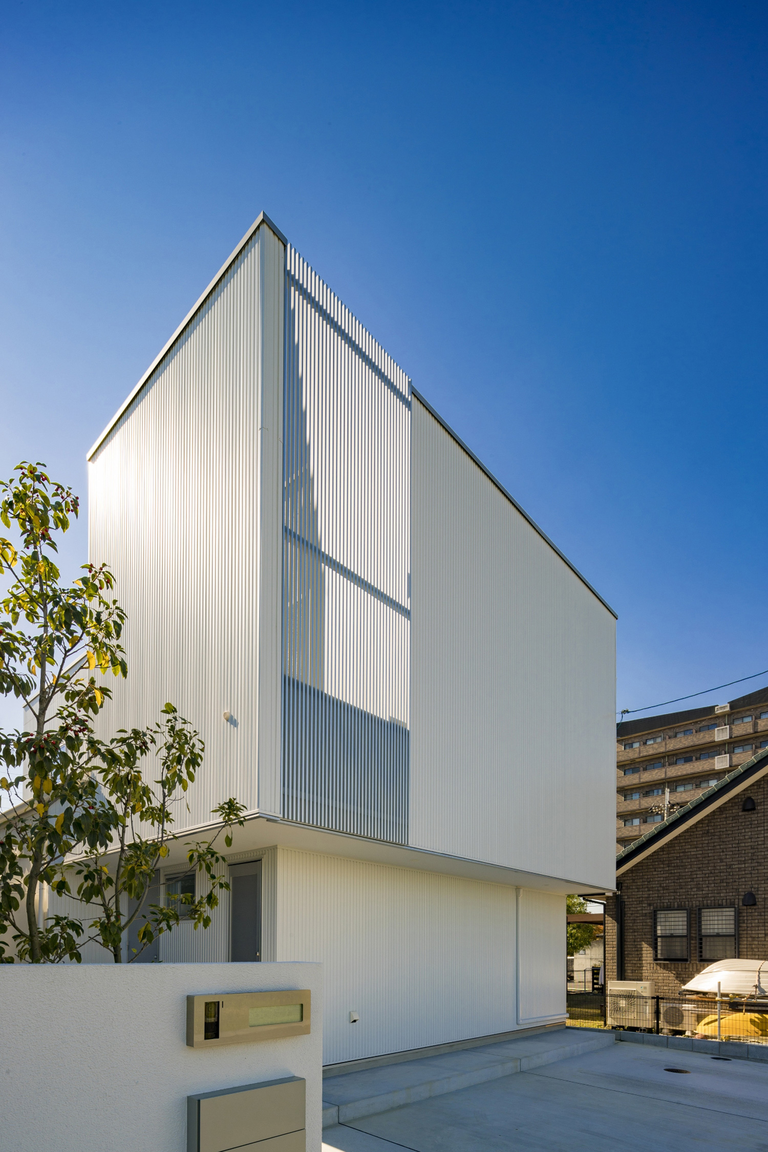 白いガルバリウム鋼板とアルミのルーバーの外壁の家を斜めから見た様子・デザイン住宅 注文住宅・デザイン住宅建築実例_『CASE598 爽 ~風と光~』_外観