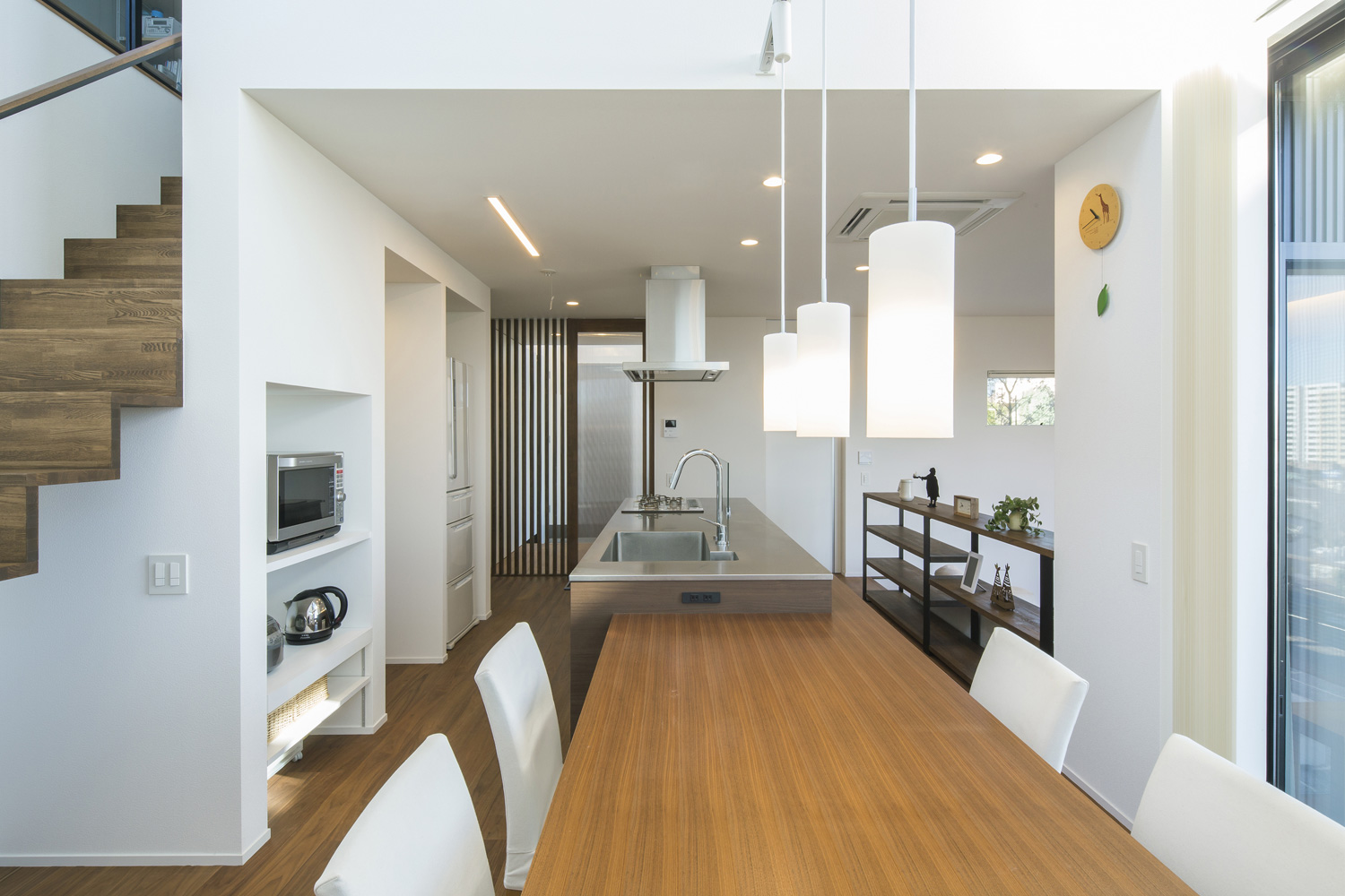 キッチンと一体化したダイニングテーブルがペンダントライトに照らされる様子・デザイン住宅 注文住宅・デザイン住宅建築実例_『CASE600 ソラの家』_LDK