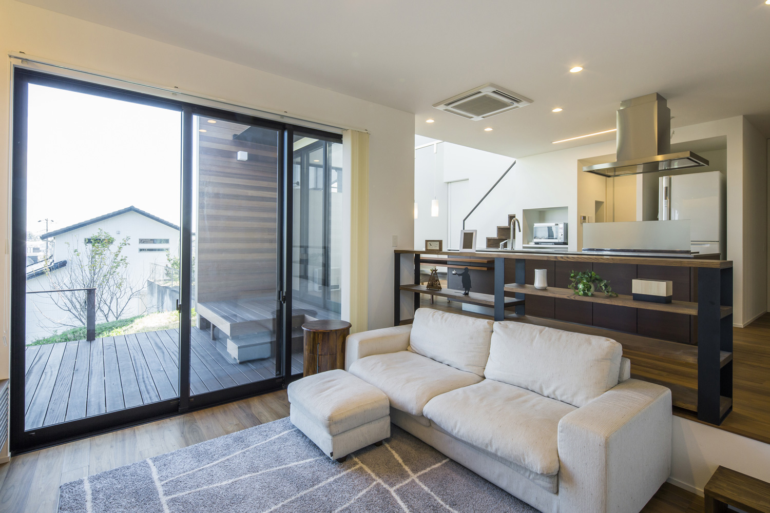 ウッドデッキのテラスとフラットに繋がるL字ソファーを置いたLDK・デザイン住宅 注文住宅・デザイン住宅建築実例_『CASE600 ソラの家』_LDK