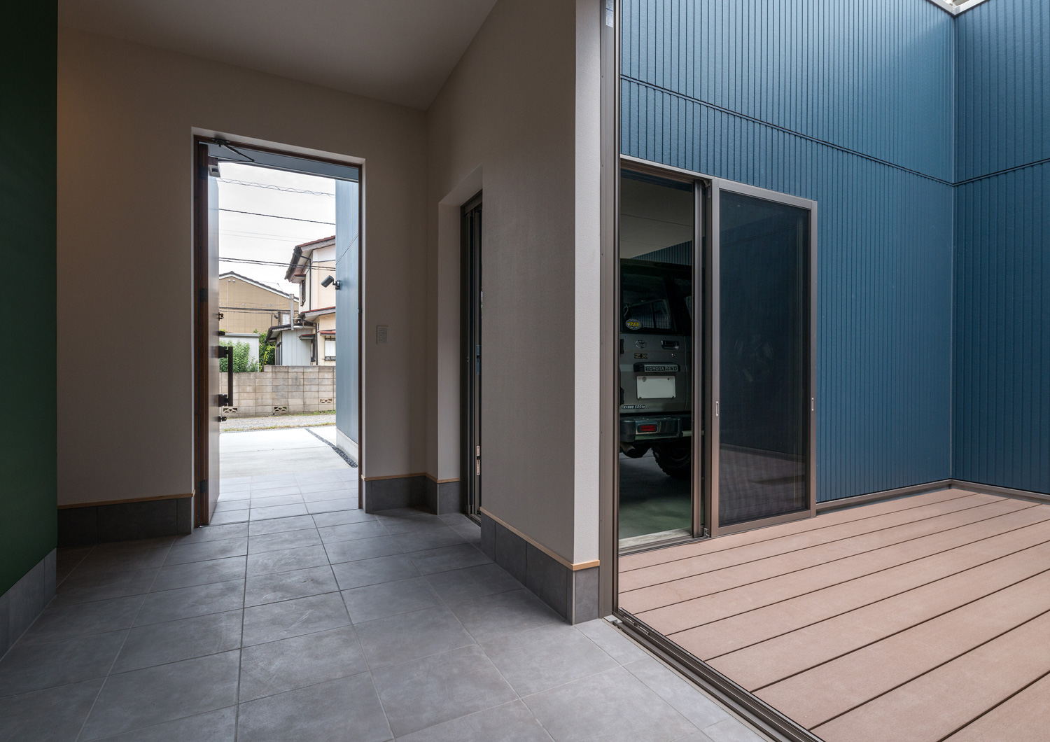 ウッドデッキの中庭と繋がる、玄関扉が開かれた土間の玄関・デザイン住宅 注文住宅・デザイン住宅建築実例_『CASE601 ドマノイエ』_玄関