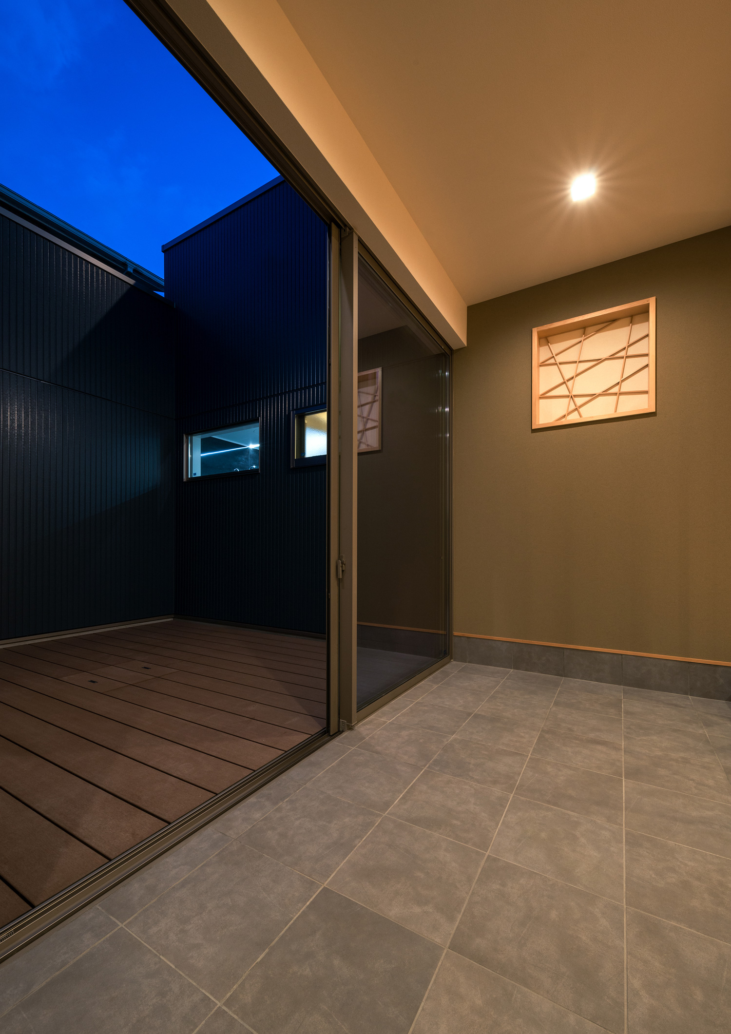 ウッドデッキの中庭とフラットに繋がるグレーのタイルの玄関・デザイン住宅 注文住宅・デザイン住宅建築実例_『CASE601 ドマノイエ』_中庭