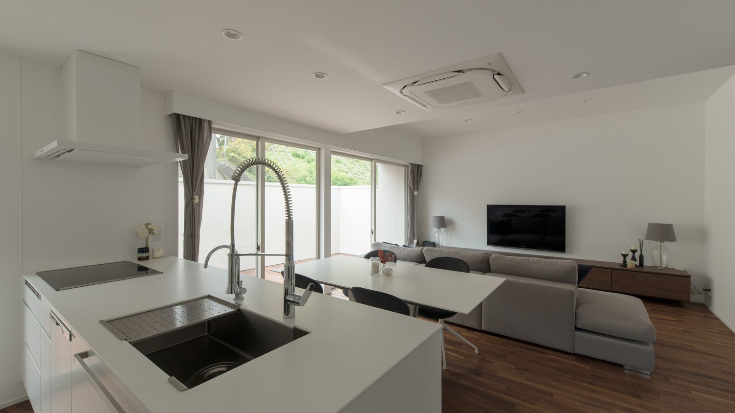 白いペニンシュラキッチンの正面に白いダイニングテーブルがあるLDK・デザイン住宅 注文住宅・デザイン住宅建築実例_『CASE602 WOODボックスハウス』_LDK