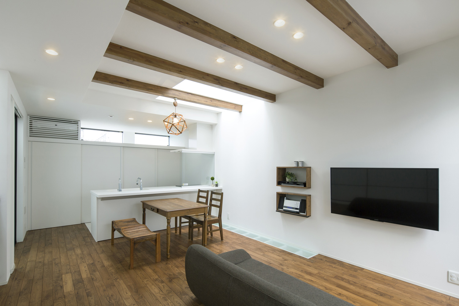 白いペニンシュラキッチンの前に木製のダイニングテーブルがある梁見せ天井のLDK・デザイン住宅 注文住宅・デザイン住宅建築実例_『CASE603 Flügel』_LDK