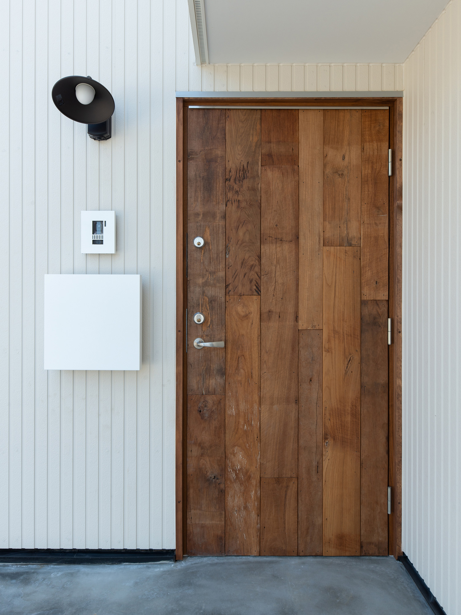 白い壁に木製の扉が取り付けられた玄関ポーチ・デザイン住宅 注文住宅・デザイン住宅建築実例_『CASE609 パーゴラの家』_外観