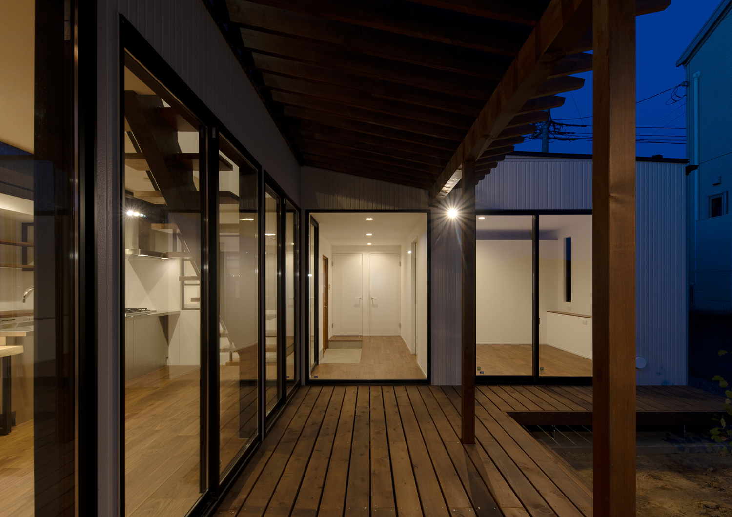 壁にスポットライトを取り付けた、室内と繋がる窓があるウッドデッキ・デザイン住宅 注文住宅・デザイン住宅建築実例_『CASE609 パーゴラの家』_テラス・バルコニー