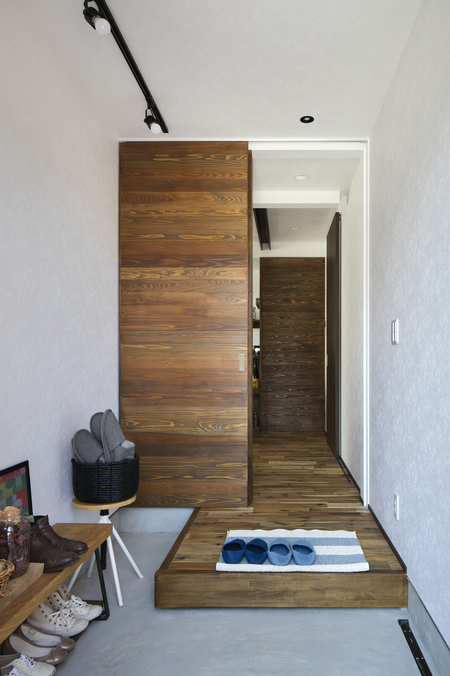 モルタルの玄関の先にフローリングや木の引き戸のあるフロアが広がる様子・デザイン住宅 注文住宅・デザイン住宅建築実例_『CASE610 Lagom hus ちょうどいい家』_玄関