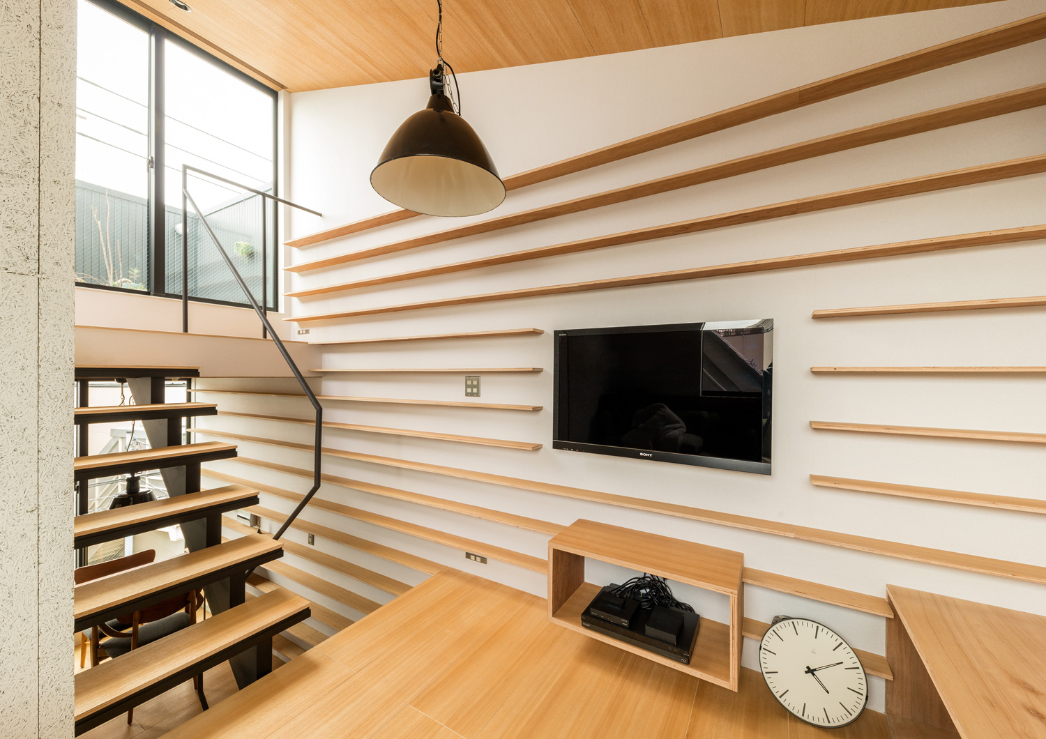 壁一面に木の棚が取り付けられたスキップフロアのLDK・デザイン住宅 注文住宅・デザイン住宅建築実例_『CASE612 たなのいえ』_LDK