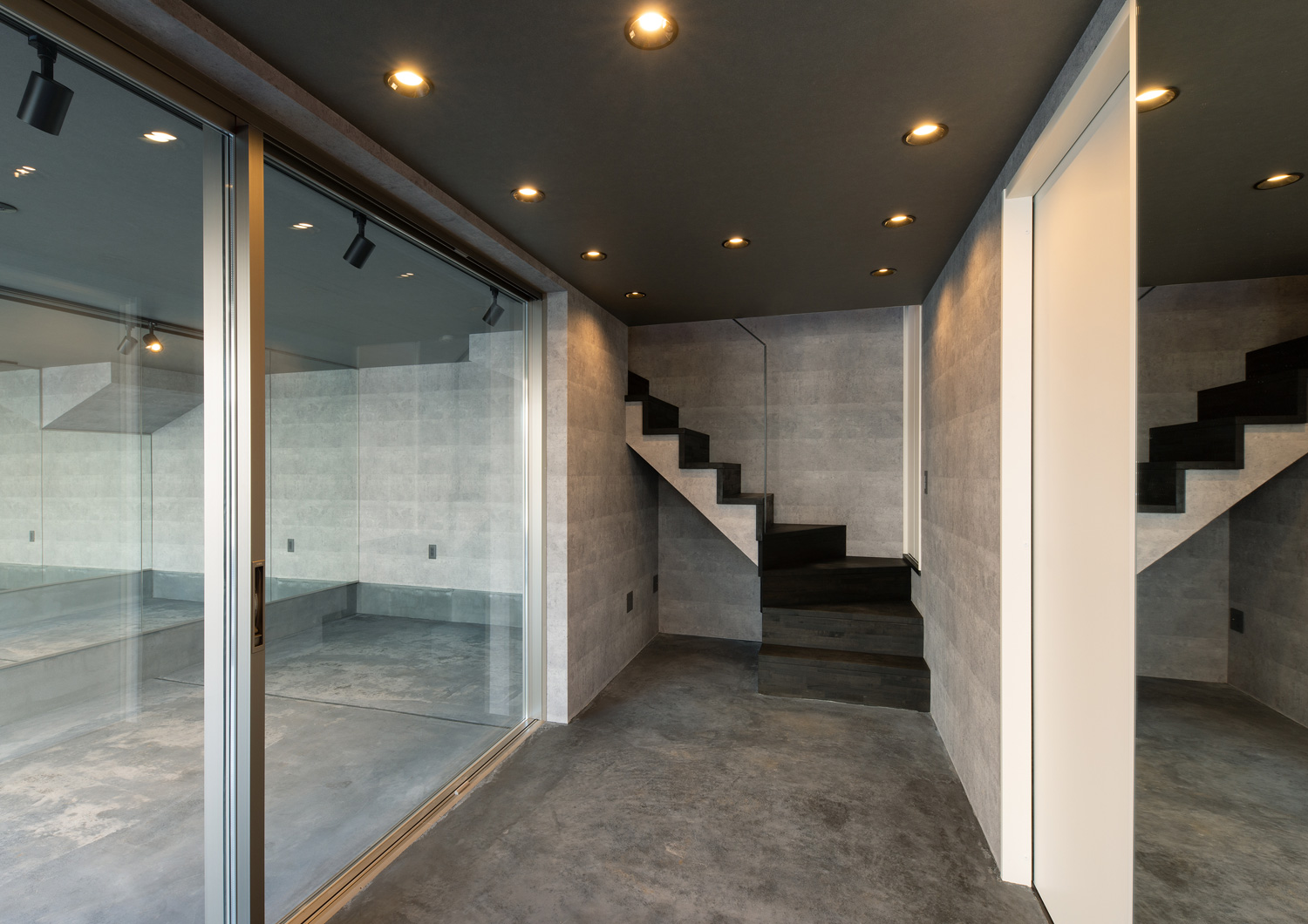 ガラス扉越しにガレージの様子が見える土間の玄関・デザイン住宅 注文住宅・デザイン住宅建築実例_『CASE617 Casa di Nero』_玄関