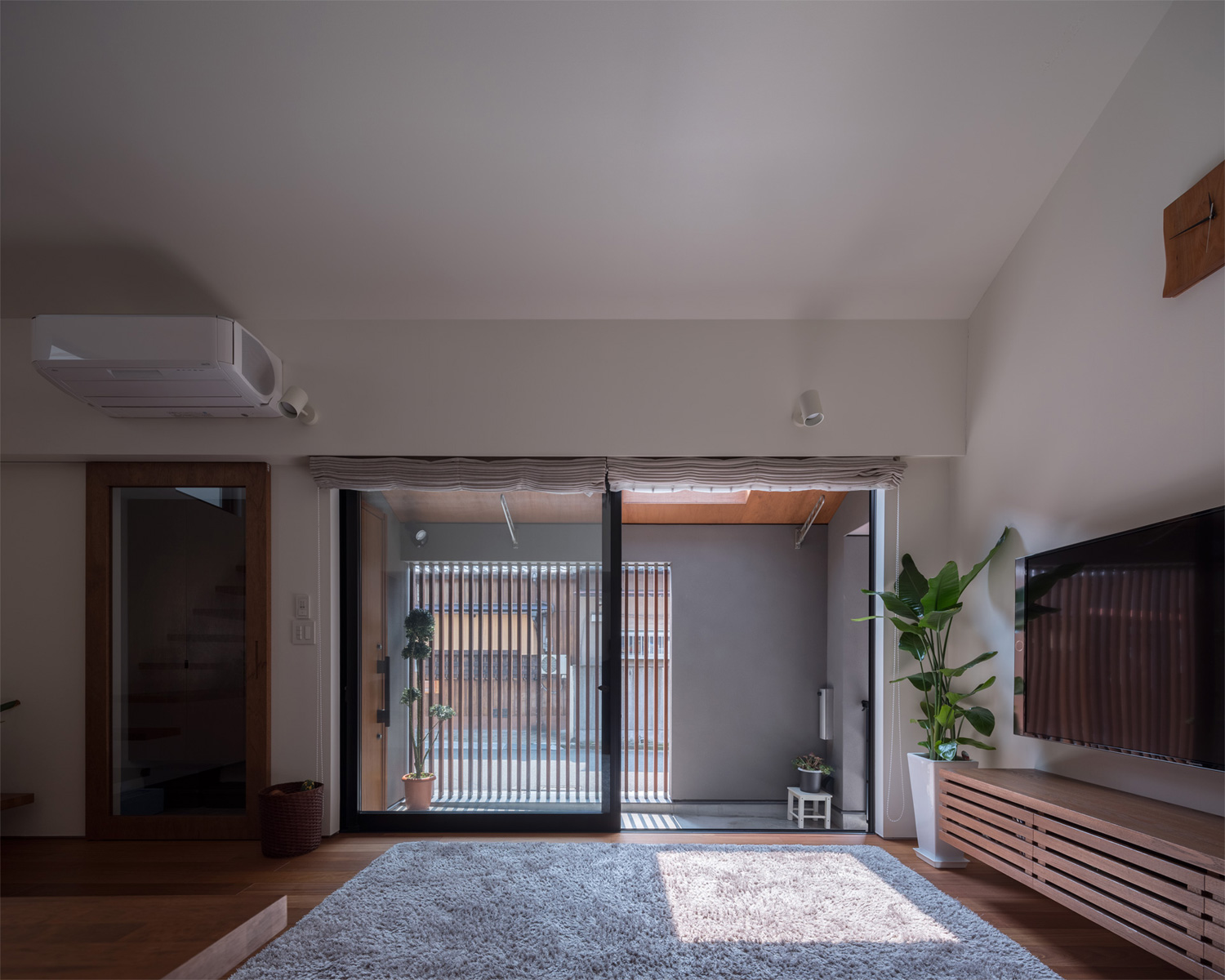 ルーバーの目隠しがあるアプローチに面した大開口窓がある、グレーのカーペットのLDK・デザイン住宅 注文住宅・デザイン住宅建築実例_『CASE622 fit』_LDK