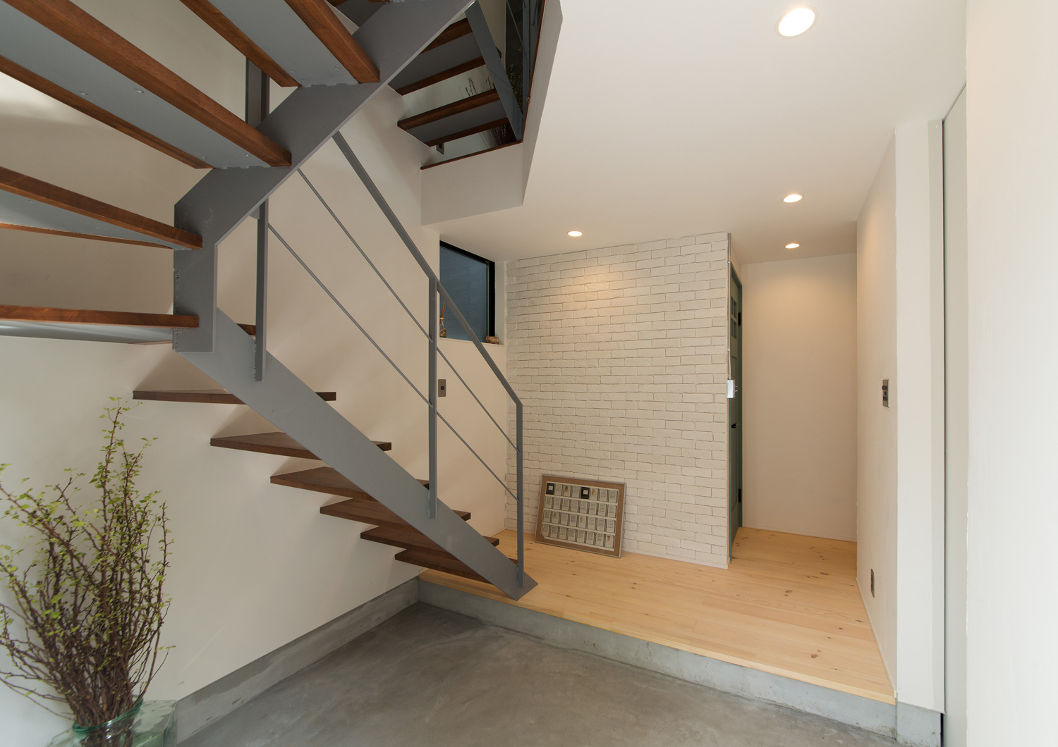 モルタルの玄関を横切るようにスケルトン階段がある様子・デザイン住宅 注文住宅・デザイン住宅建築実例_『CASE626 Triangle』_玄関