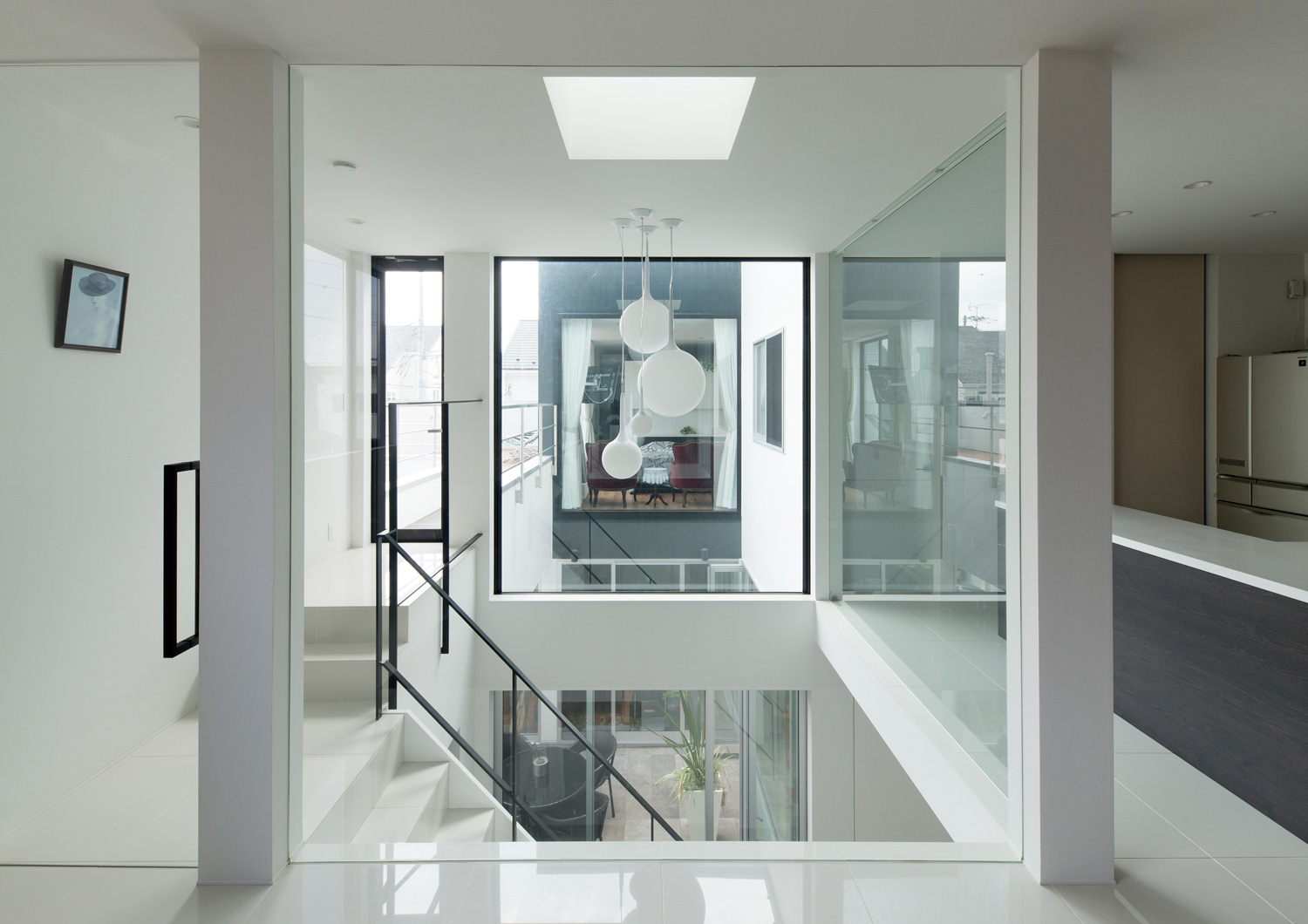 ガラスの壁越しに吹き抜けの階段部分が見えるLDK・デザイン住宅 注文住宅・デザイン住宅建築実例_『CASE593 CAMP』_LDK