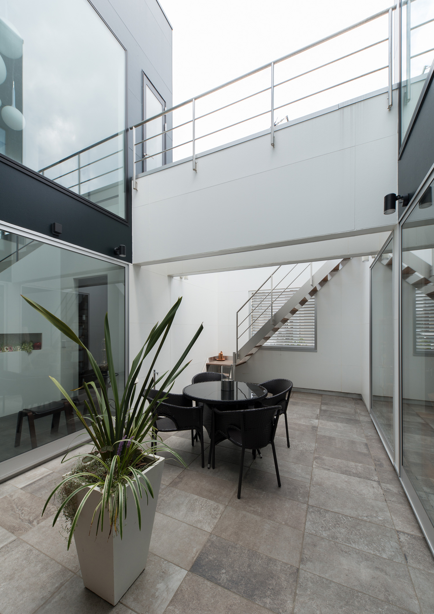 渡り廊下を設けたテーブルや観葉植物を置いた中庭・デザイン住宅 注文住宅・デザイン住宅建築実例_『CASE593 CAMP』_中庭