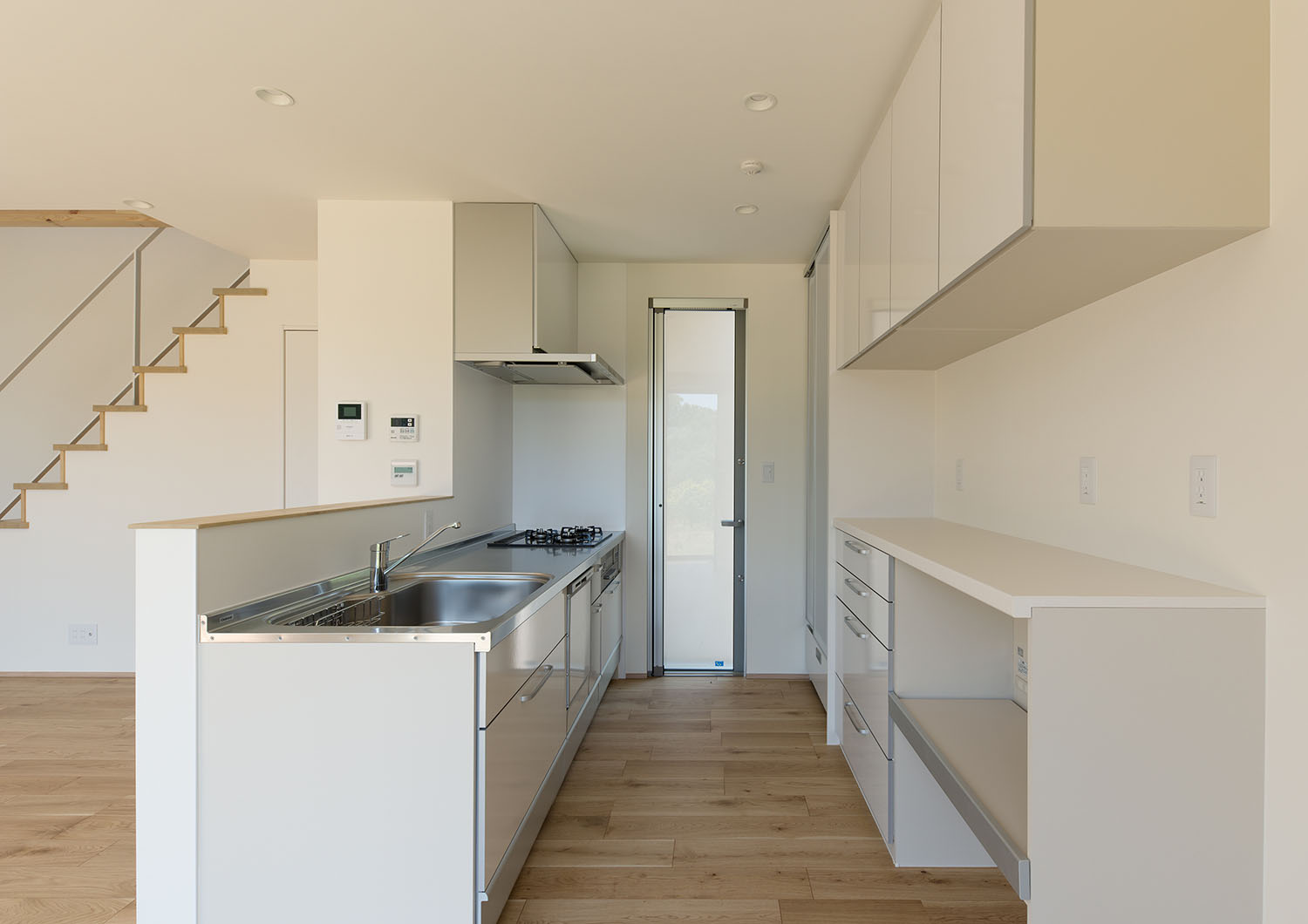 背面にカップボードを取り付けた腰壁付きの白い対面キッチン・デザイン住宅 注文住宅・デザイン住宅建築実例_『CASE550 three box house』_キッチン