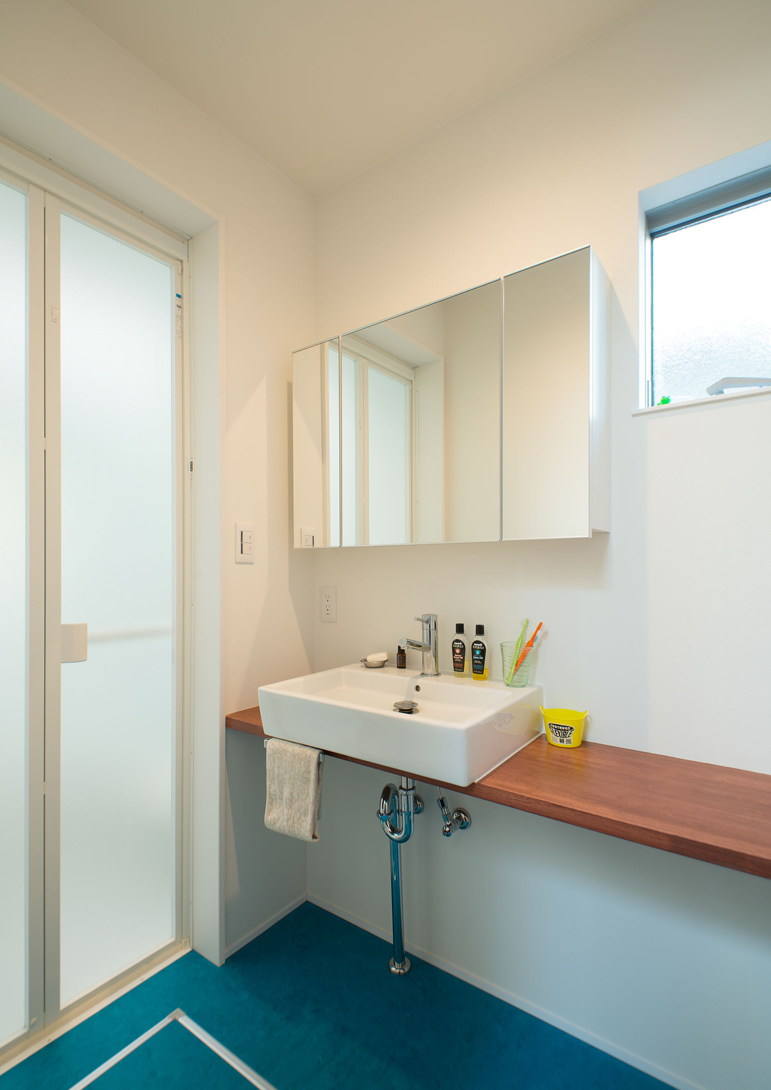 青い床で木の洗面台がある洗面所・デザイン住宅 注文住宅・デザイン住宅建築実例_『CASE625 ヒカリの家』_浴室・洗面所
