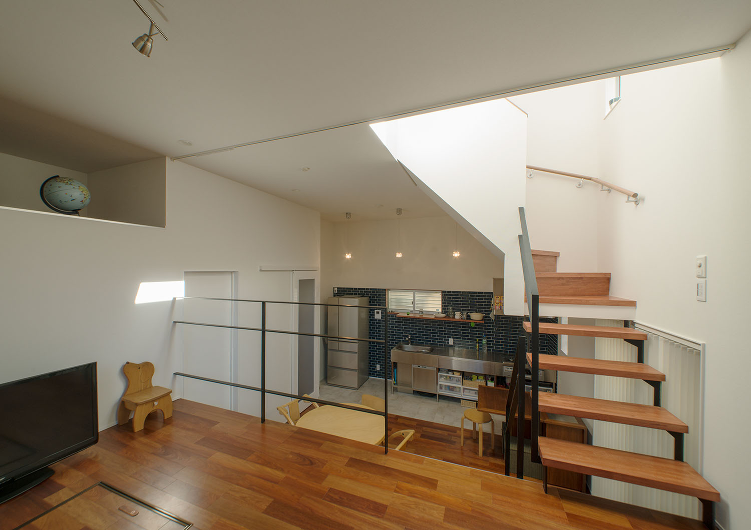 スキップフロアから、キッチンや丸いテーブルがあるダイニングを見た様子・デザイン住宅 注文住宅・デザイン住宅建築実例_『CASE625 ヒカリの家』_LDK