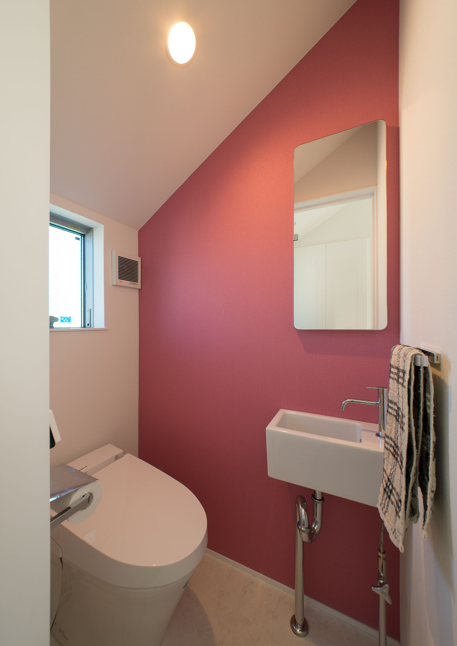 ピンク色のアクセントクロスや薄型手洗いがある、母屋下がりのトイレ・デザイン住宅 注文住宅・デザイン住宅建築実例_『CASE625 ヒカリの家』_トイレ