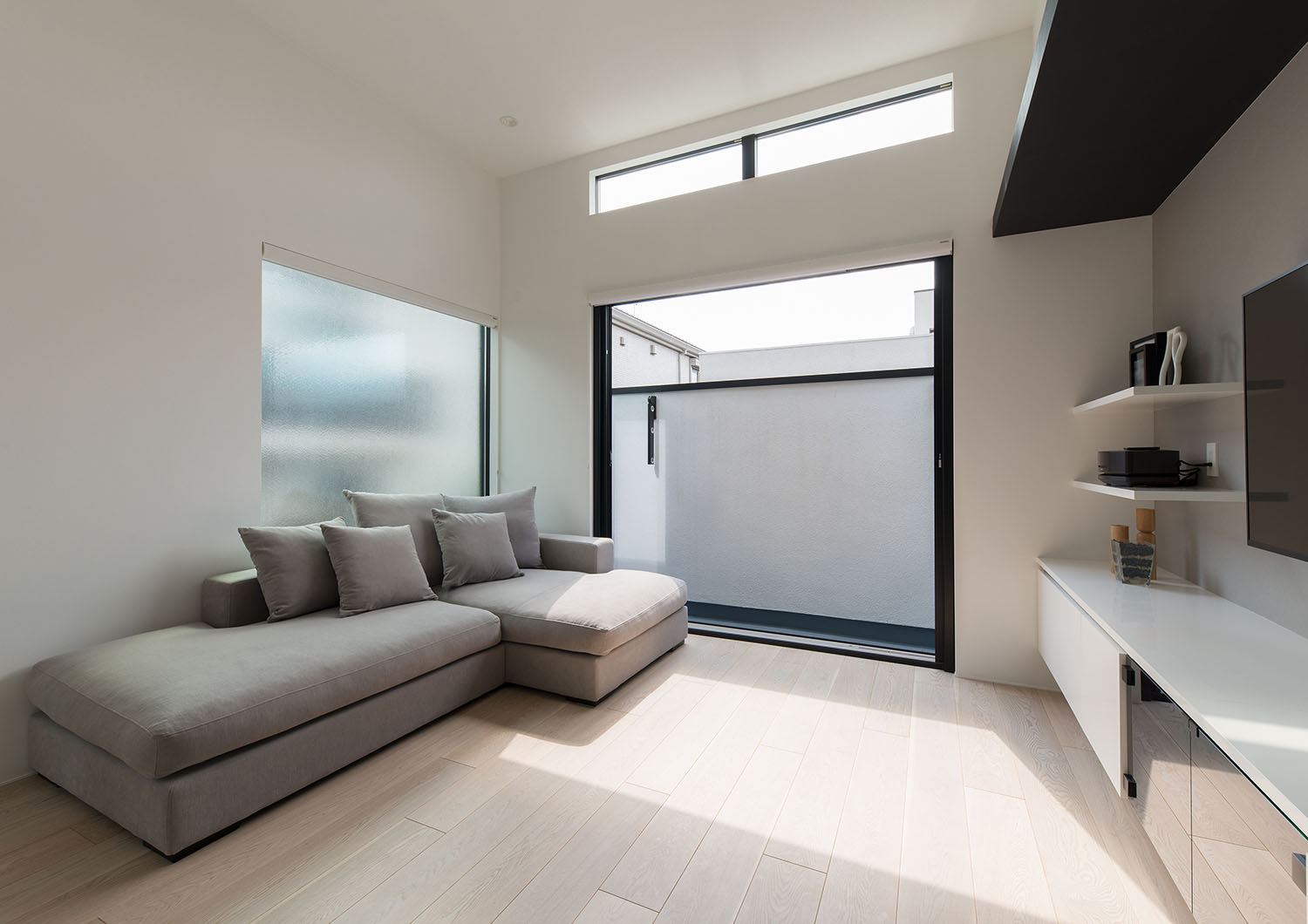 バルコニーに面した窓の上にハイサイドライトを設けたL字ソファーのあるLDK・デザイン住宅 注文住宅・デザイン住宅建築実例_『CASE597 Ambiguous Expression』_LDK