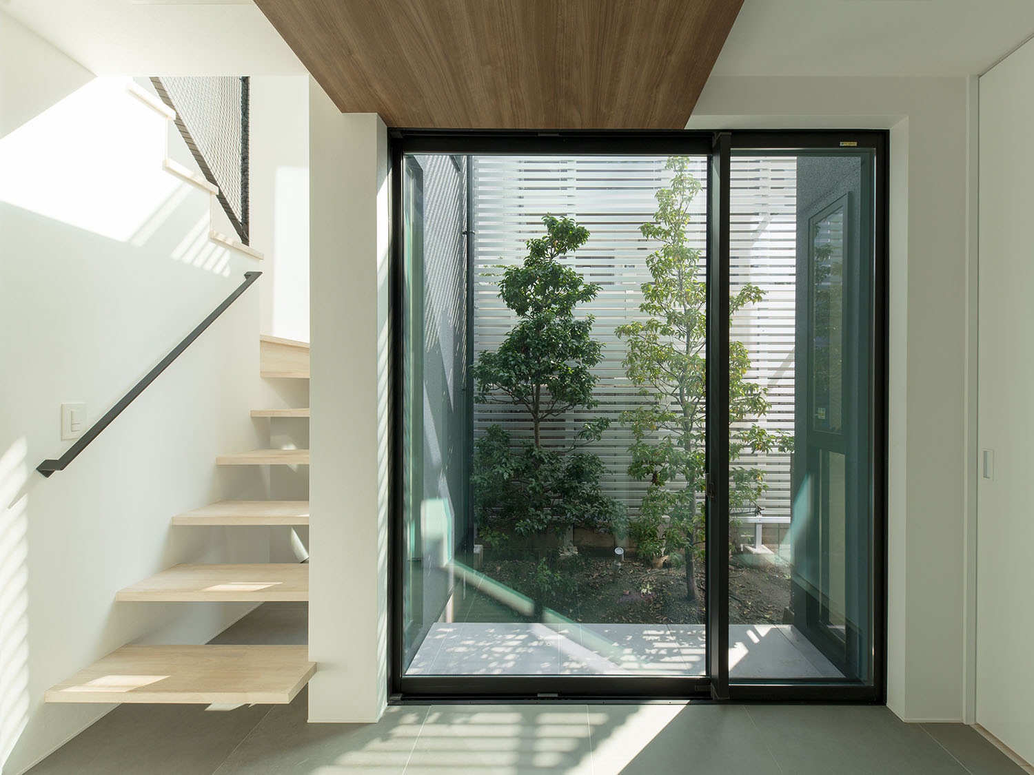 植栽のある中庭に面した窓の隣にある白いスケルトン階段・デザイン住宅 注文住宅・デザイン住宅建築実例_『CASE597 Ambiguous Expression』_中庭