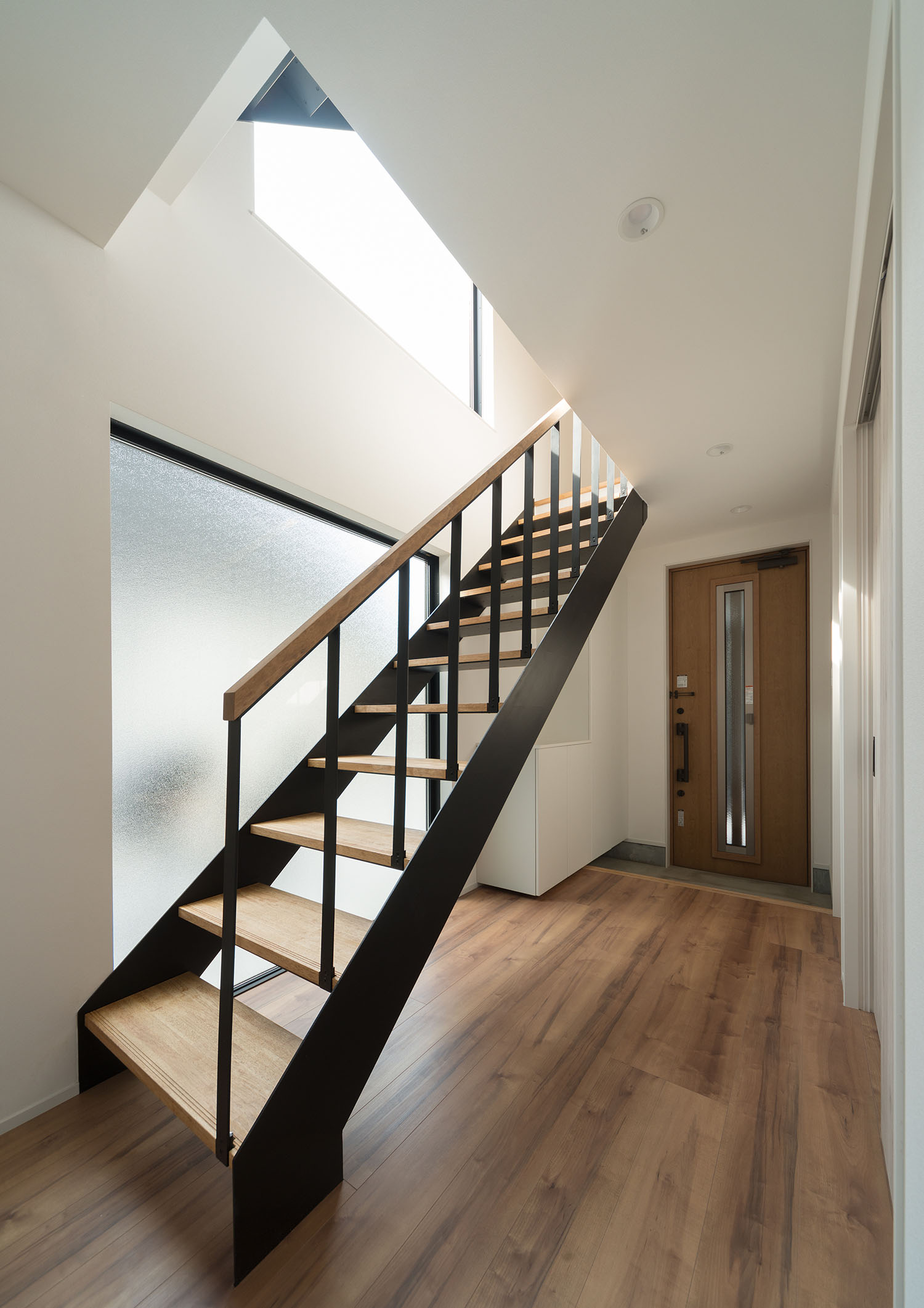 曇りガラスの大きな窓と木製のスケルトン階段がある廊下・デザイン住宅 注文住宅・デザイン住宅建築実例_『CASE599 日向ぼっこしたくなる階段のある家』_玄関