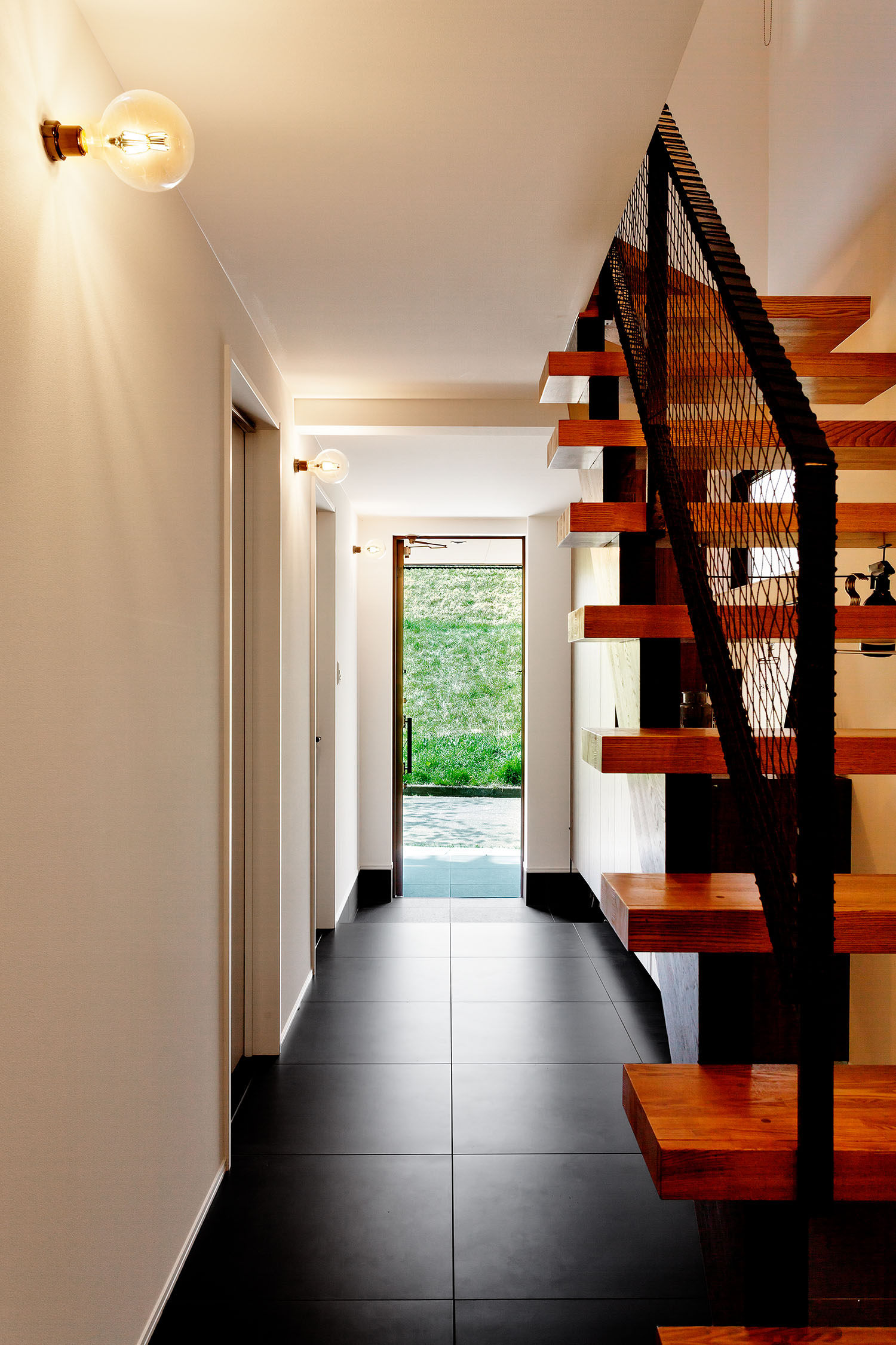 黒いタイル張りの玄関から、外の景色が見える様子・デザイン住宅 注文住宅・デザイン住宅建築実例_『CASE604 “LIKE”』_玄関