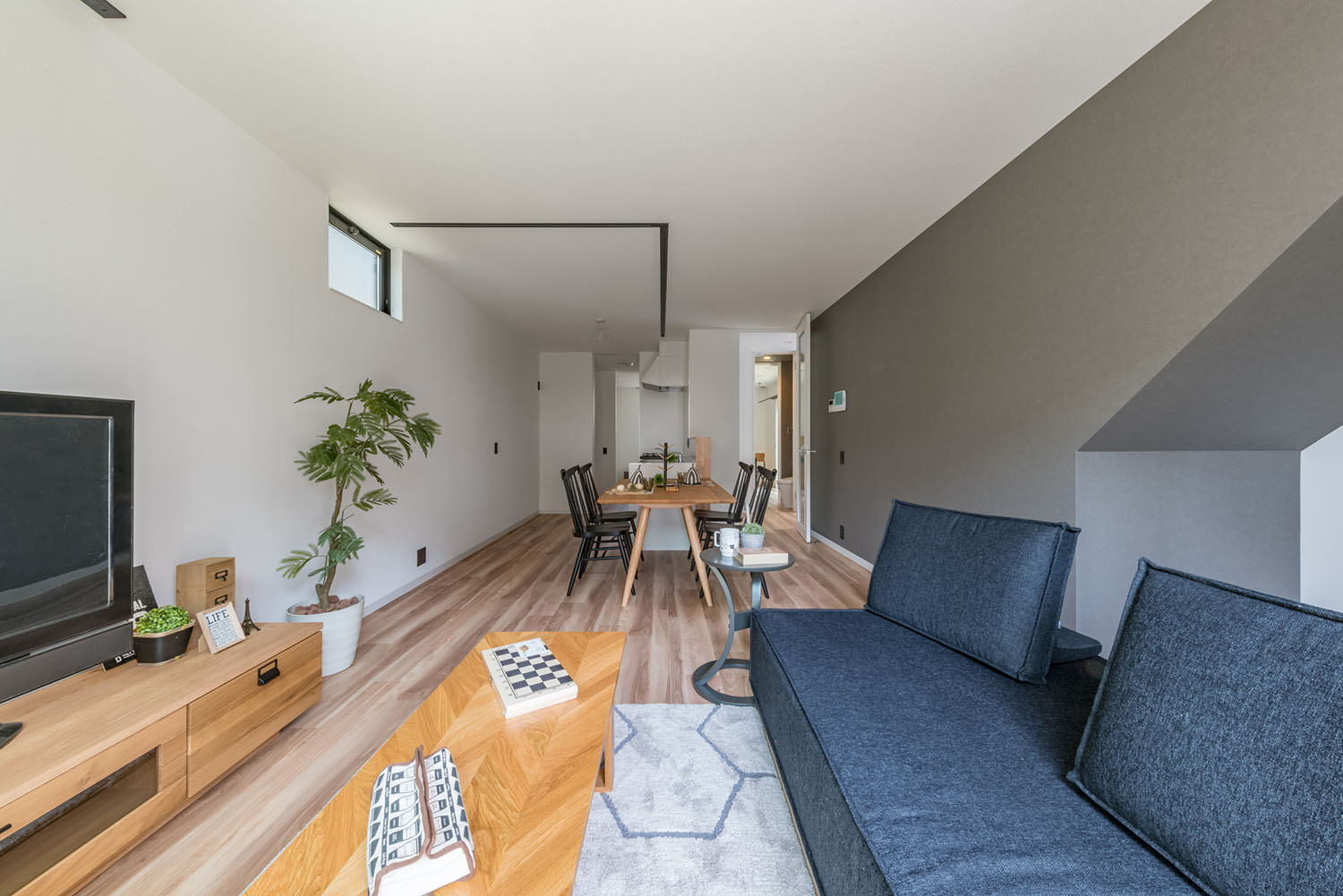 デニムのソファーや木のサイドテーブルが置かれたフローリングのLDK・デザイン住宅 注文住宅・デザイン住宅建築実例_『CASE623 HOUSest-Life+Cafe』_LDK