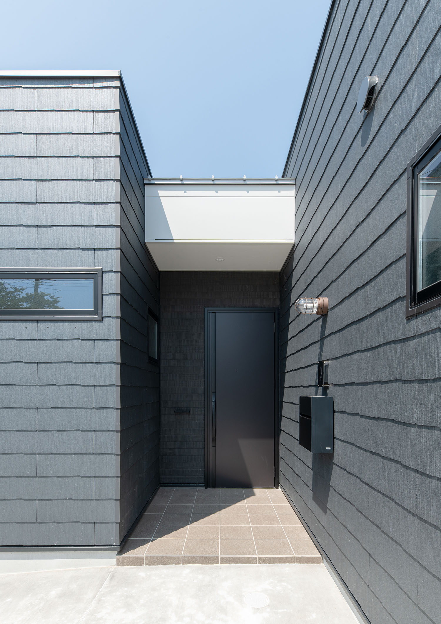 黒い外壁と玄関扉に、白い庇がついた玄関・デザイン住宅 注文住宅・デザイン住宅建築実例_『CASE685 flat scale』_外観