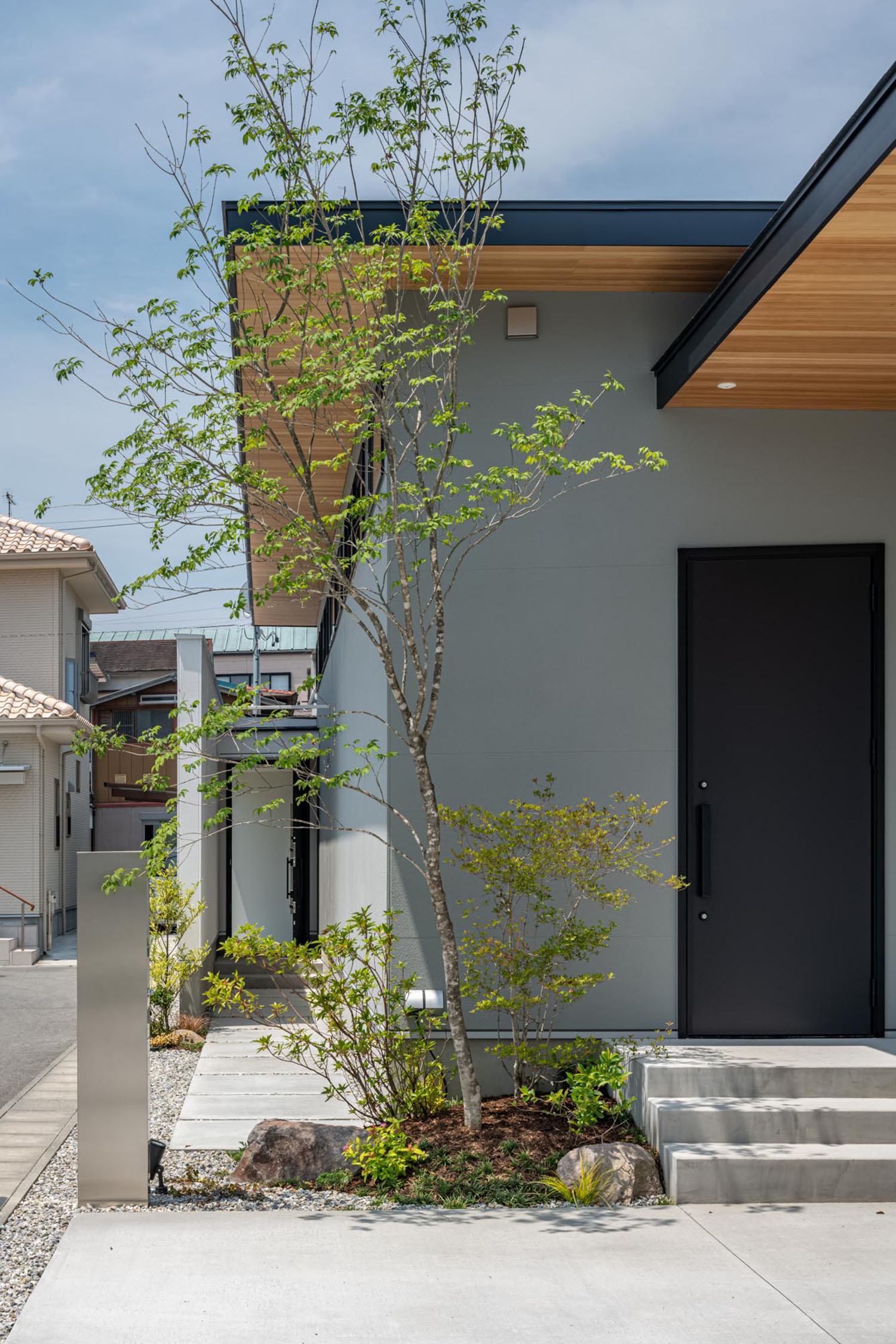 グレーの外壁の住宅の前に一本の植栽が植えられている様子・デザイン住宅 注文住宅・デザイン住宅建築実例_『CASE686 桜並木の平屋』_外観