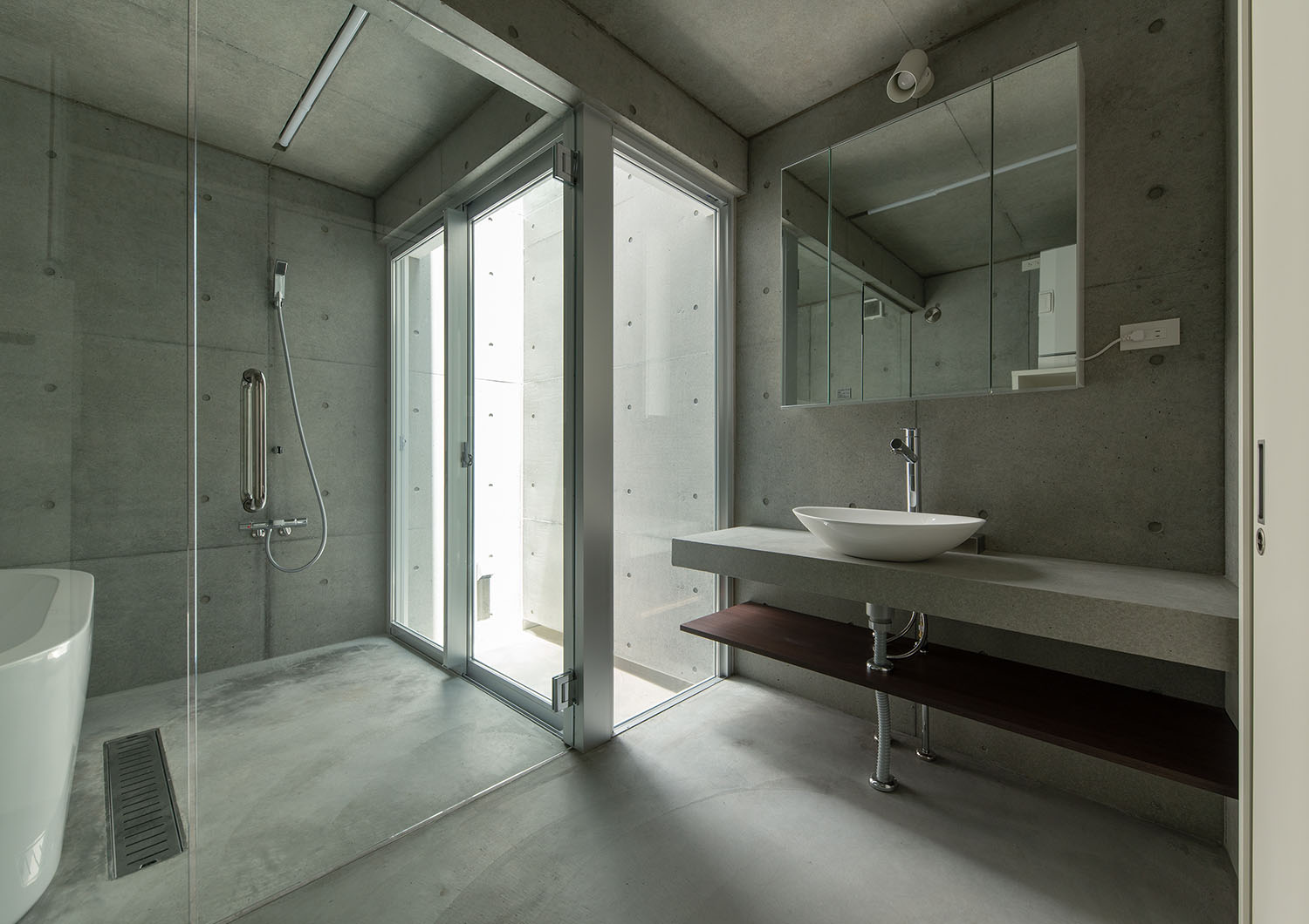 ガラス扉で仕切られているコンクリート壁の洗面所と浴室・デザイン住宅 注文住宅・デザイン住宅建築実例_『CASE691 MateriaBox』_浴室・洗面所