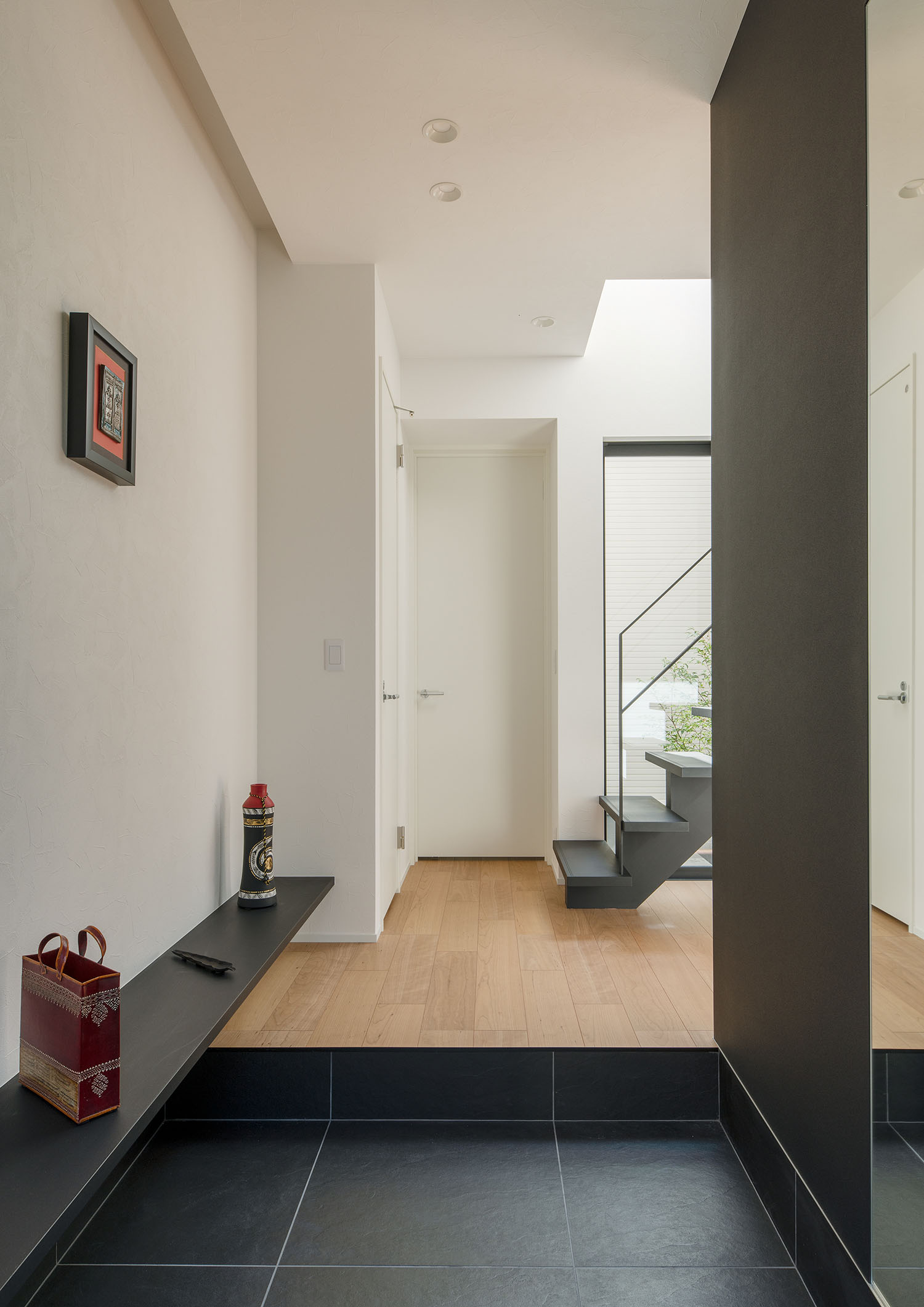 黒のタイルの玄関の正面に白い扉や階段が見える様子・デザイン住宅 注文住宅・デザイン住宅建築実例_『CASE693 "CONNECT"』_玄関