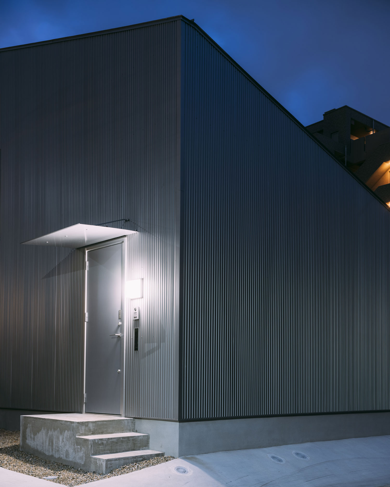 外壁に設けられた照明が、玄関扉を照らしている様子・フリーダムアーキテクツの事例 注文住宅・デザイン住宅建築実例_『CASE703 /』_外観