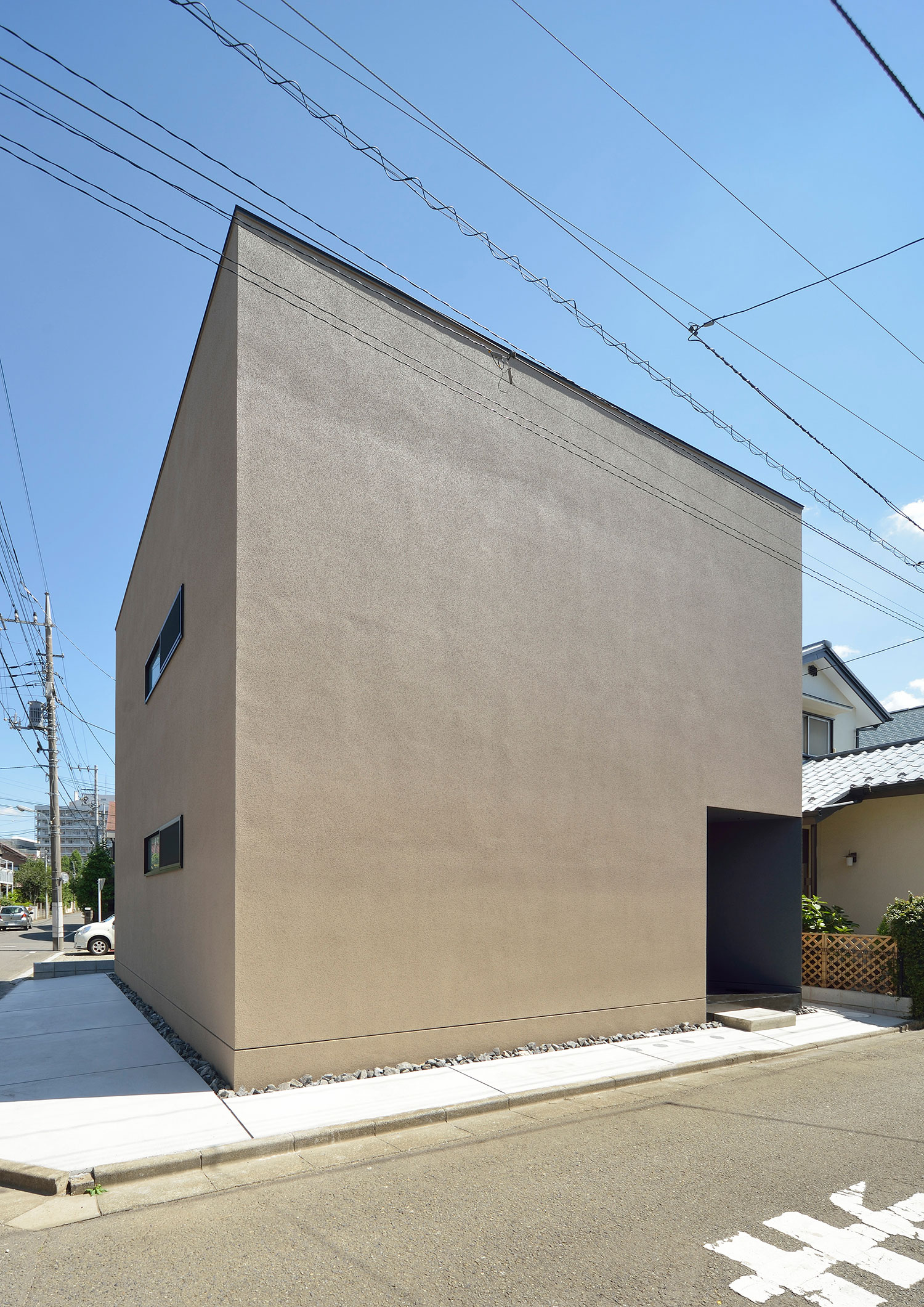 窓のないベージュのキューブ状の外観の家・デザイン住宅