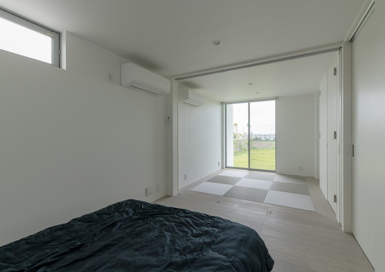 黒いベッドのある寝室から和室や芝生の庭が見える様子・デザイン住宅 注文住宅・デザイン住宅建築実例_『CASE750 WHITE GATE』_和室