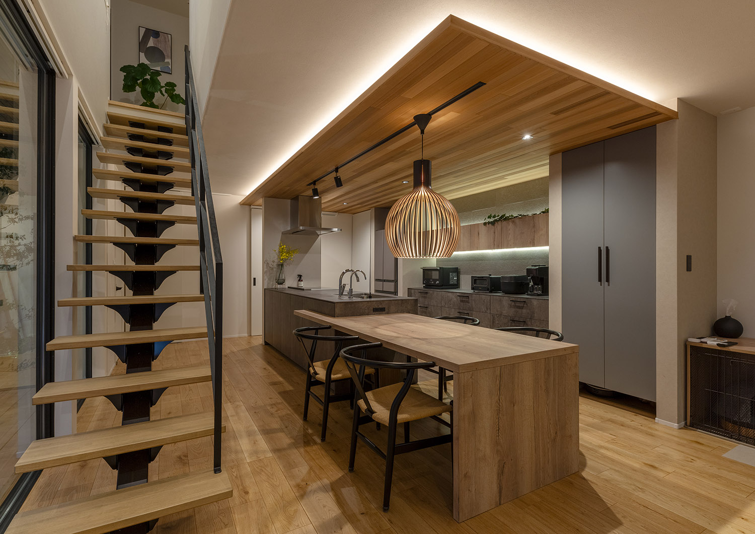 木目の下がり天井には間接照明が設けられ、ダイニングテーブルの上にペンダントライトが取り付けられた様子・デザイン住宅 注文住宅・デザイン住宅建築実例_『CASE757 トキノエンガワ』_LDK