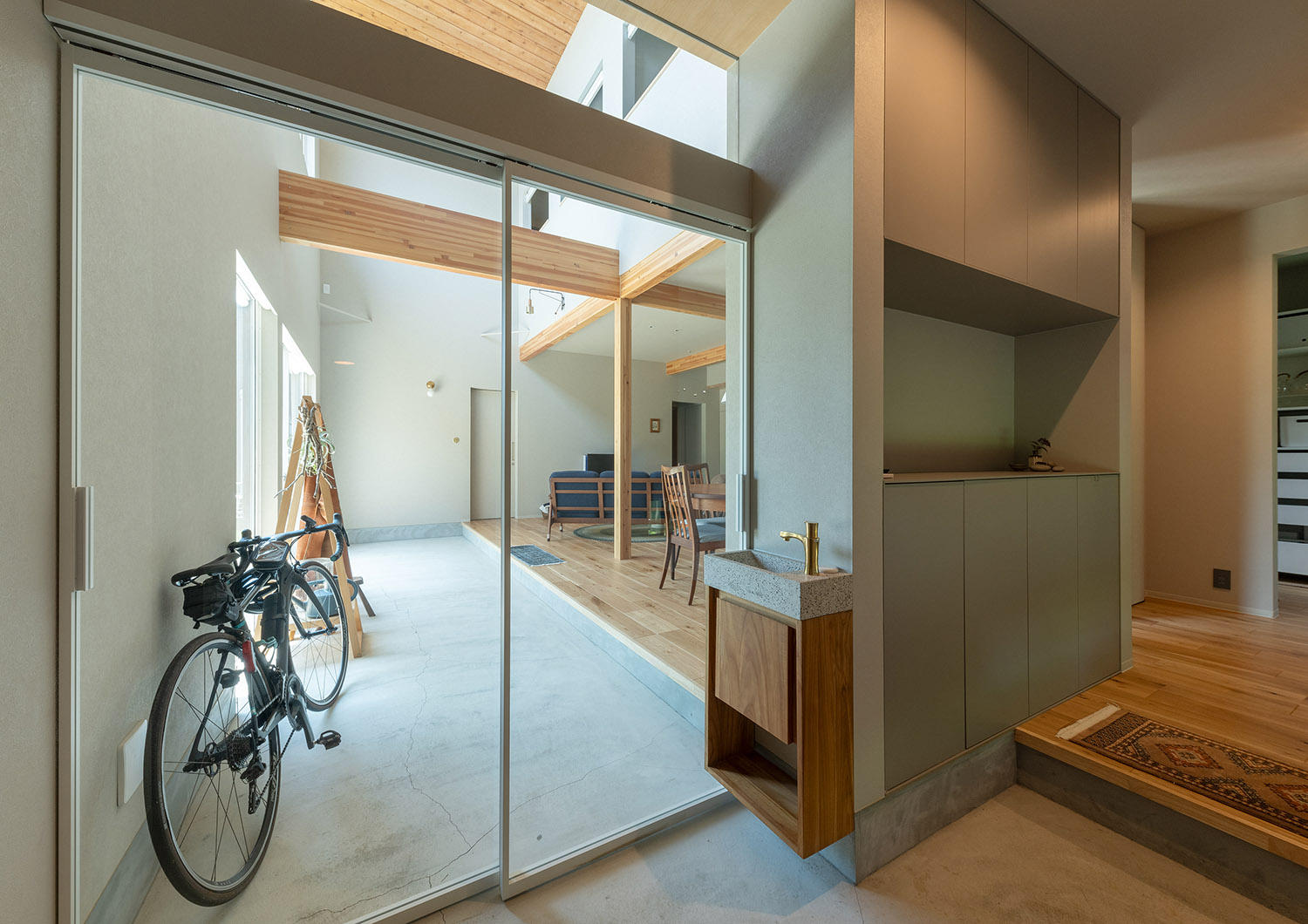 玄関と吹き抜けの土間空間がガラスで仕切られた開放的なデザイン・デザイン住宅 注文住宅・デザイン住宅建築実例_『CASE767 ウチソトのドマ』_玄関