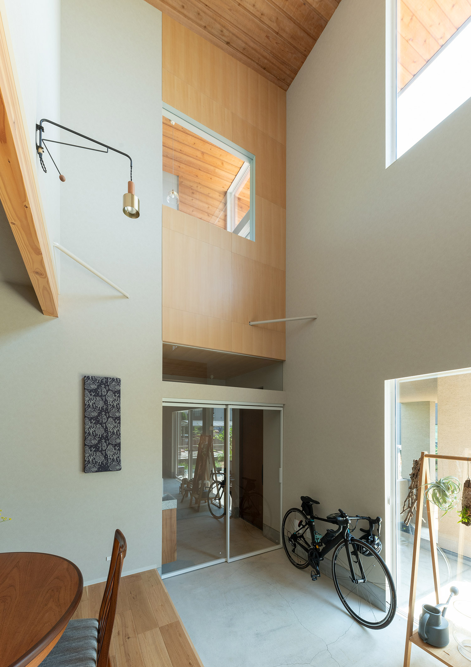 木目の壁に室内窓が取り付けられた吹き抜け・デザイン住宅 注文住宅・デザイン住宅建築実例_『CASE767 ウチソトのドマ』_LDK