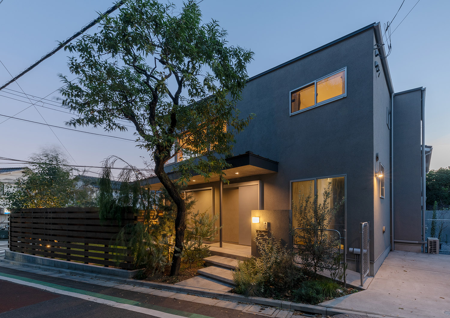 壁に照明が取り付けられた玄関アプローチがあるグレーの外壁の家・デザイン住宅 注文住宅・デザイン住宅建築実例_『CASE772 大らかにツナガル』_外観